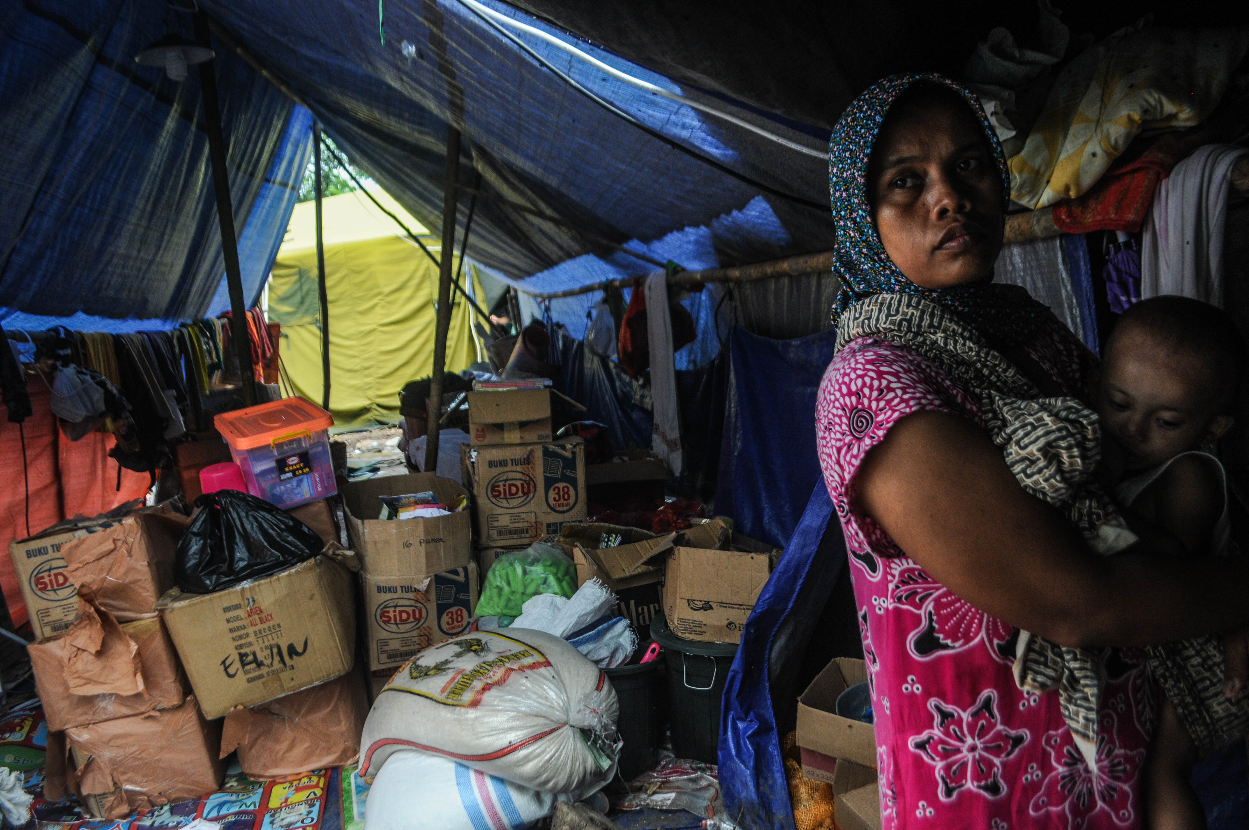 Seorang ibu menggendong anaknya di depan tenda pengungsian di Kampung Susukan, Lebak, Banten, Selasa (28/1/2020). 
