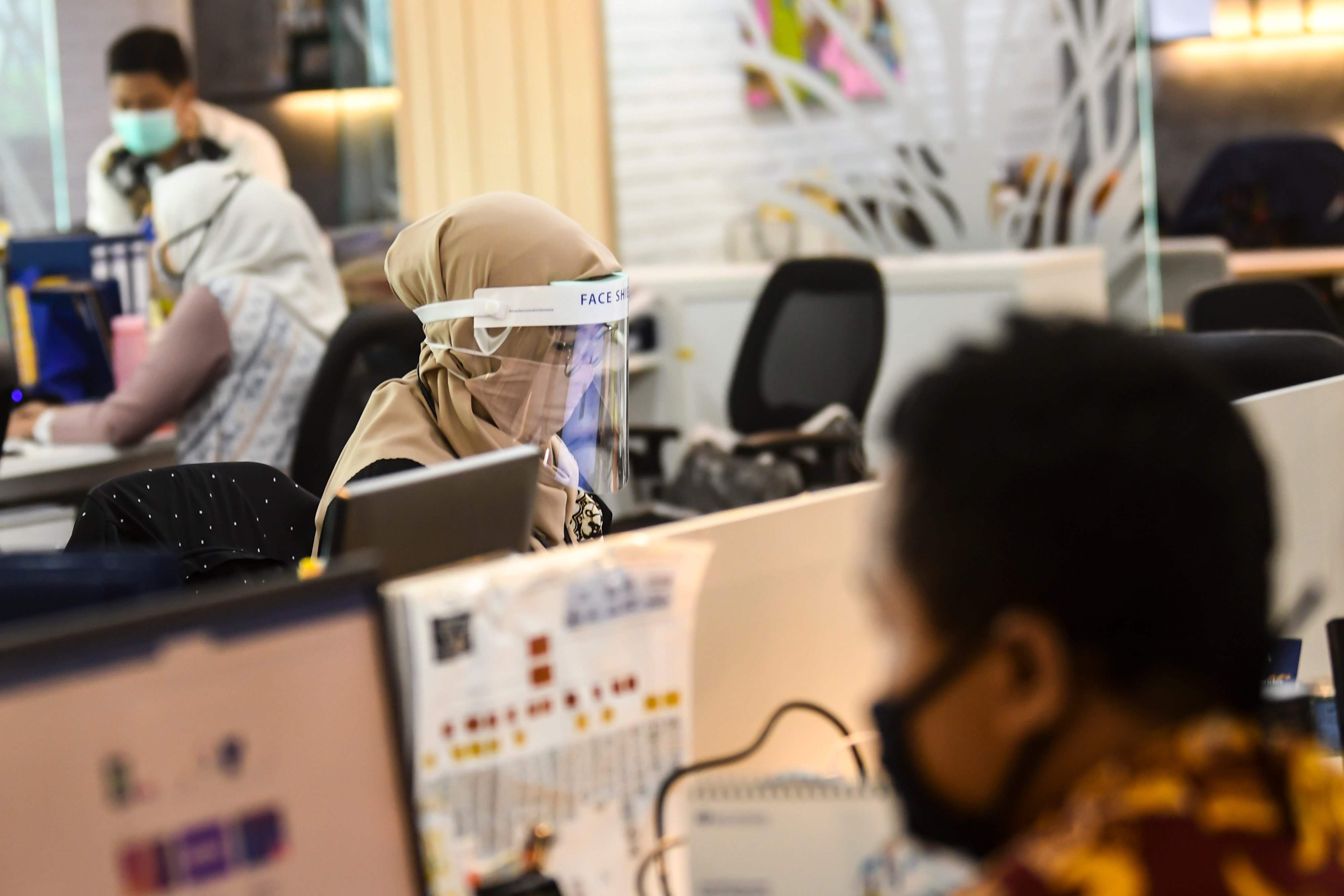 Pekerja mengenakan alat pelindung diri saat beraktivitas di kantor di tengah pandemi