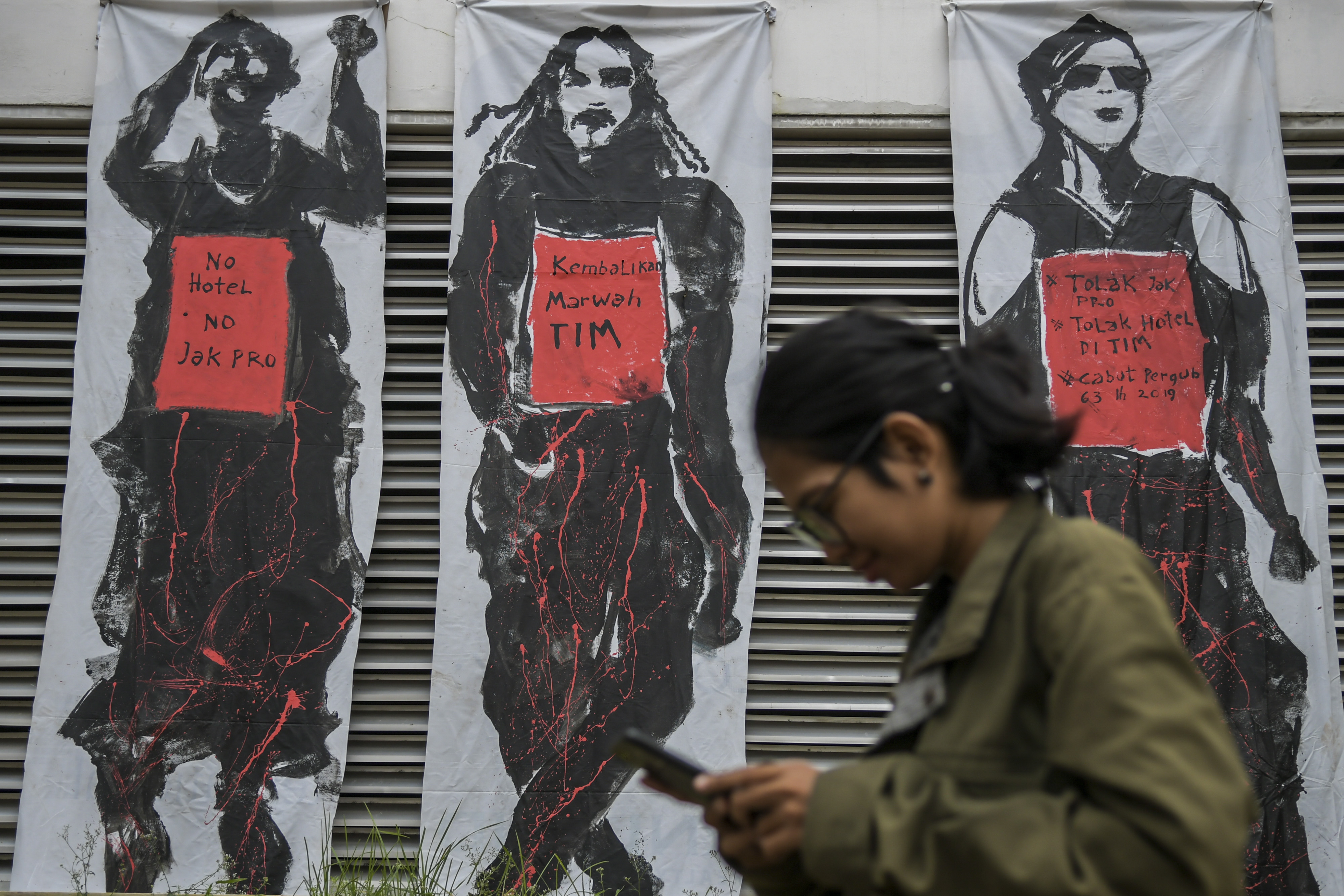 Warga melintasi mural penolakan revitalisasi kawasan Taman Ismail Marzuki (TIM), di Jakarta, Selasa (3/3/2020).