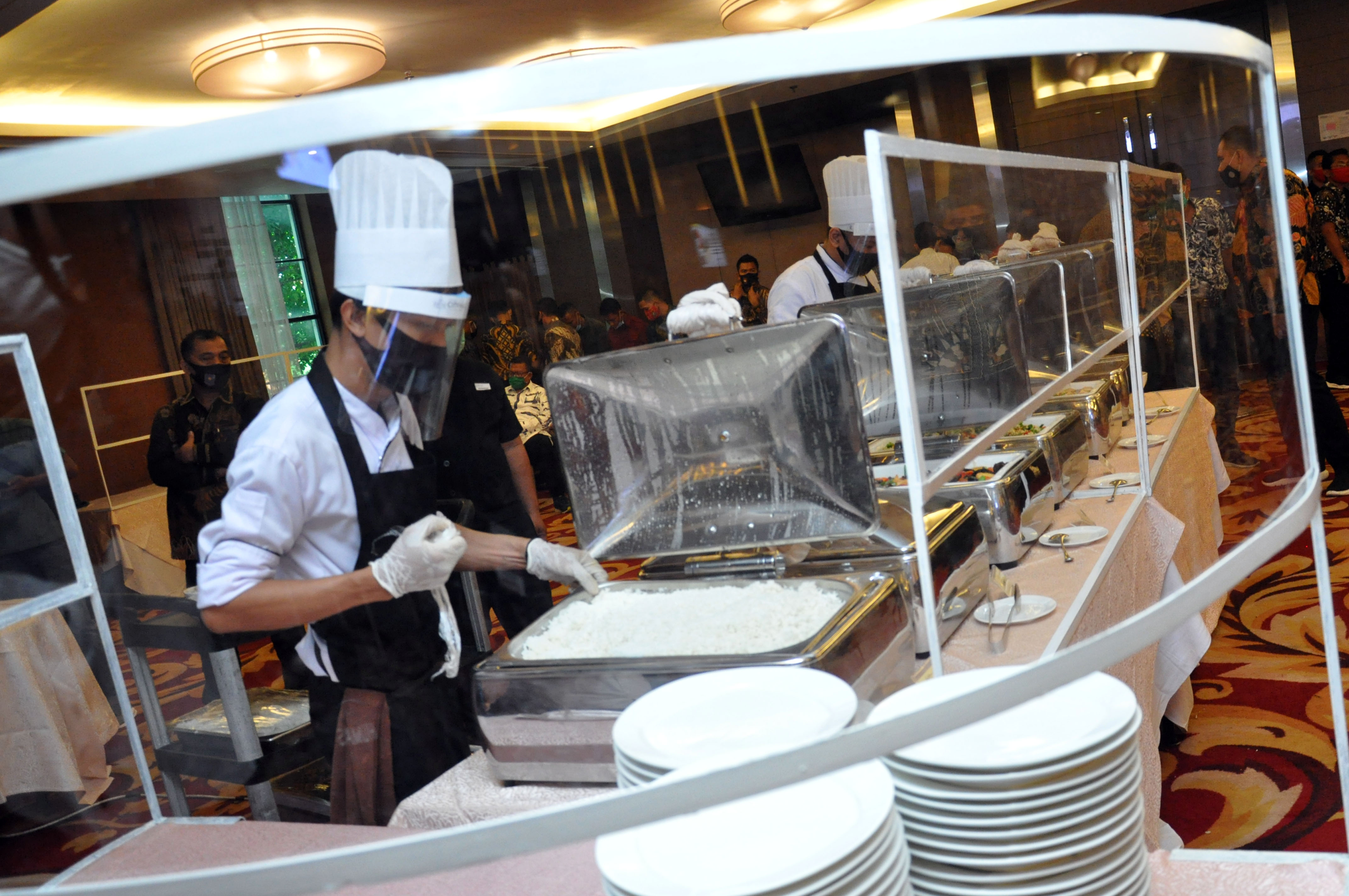uru masak hotel menyiapkan hidangan makanan dengan menggunakan alat pelindung diri dan plastik pembatas di salah satu hotel berbintang di Me