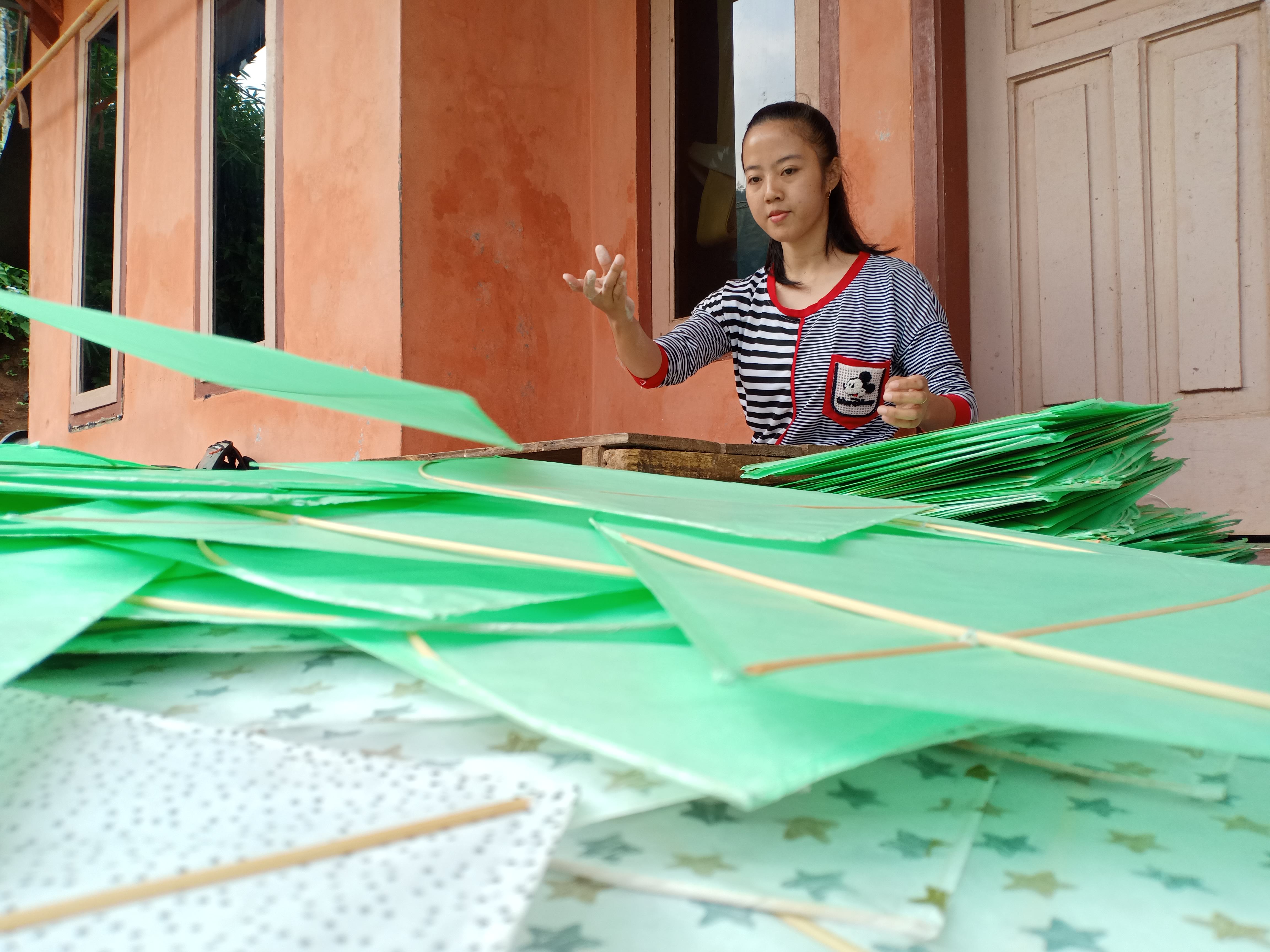 Rina, warga Kampung Pasirwangi, Desa Singajaya, Kecamatan Cihampelas, Kabupaten Bandung Barat menyelesaikan pembuatan layang-layang