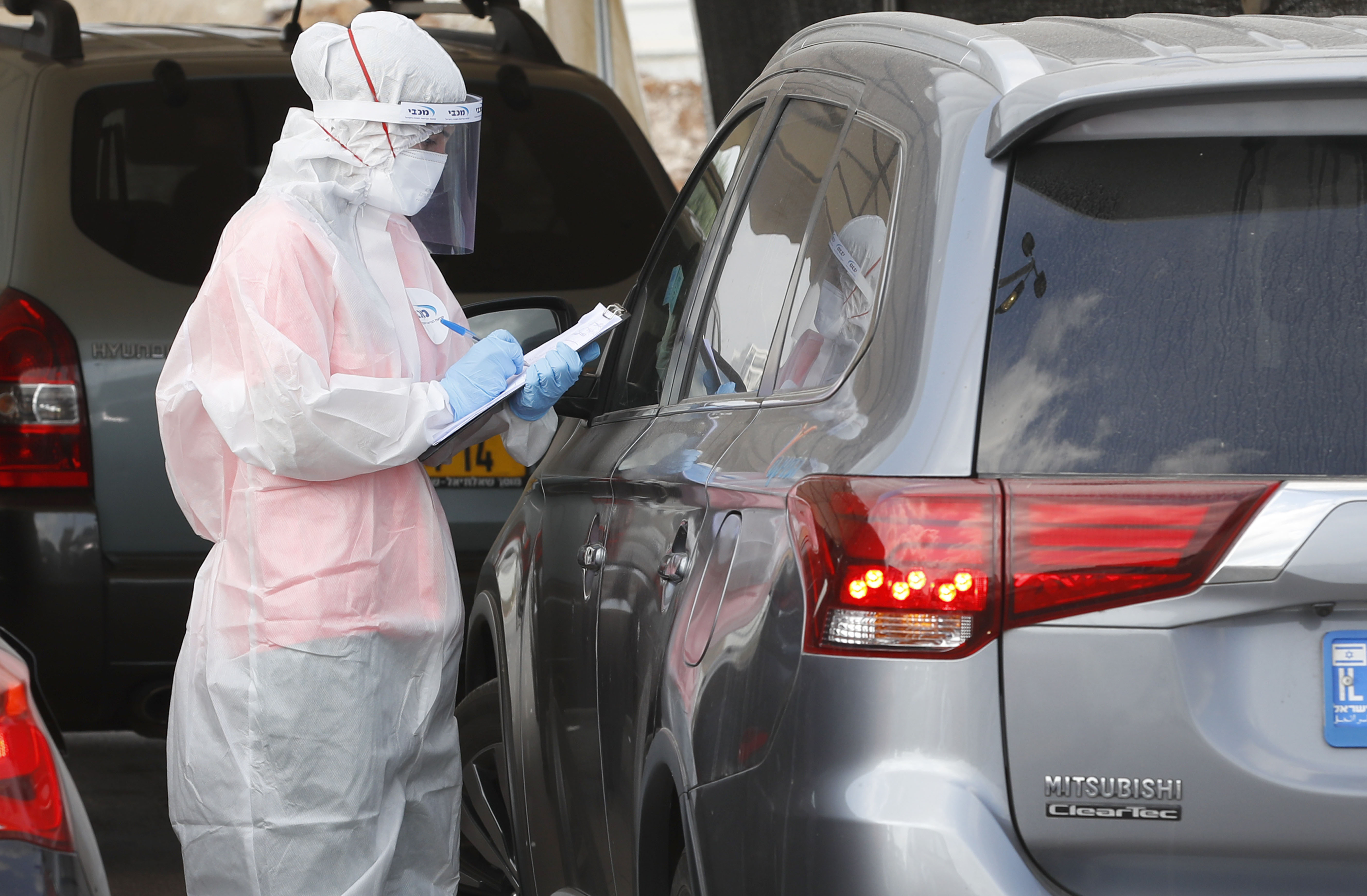 Petugas mengambil sampel di fasilitas tes covid-19 drive through di Ramat Hasharon, Tel Aviv, Israel.
