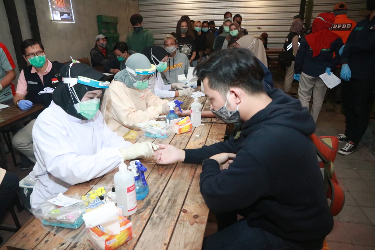 Petugas gabungan melakukan tes cepat pada pengelola cafe dan pengunjung, di jalan Terusan Candi Mendut, Kota Malang, Jawa Timur, kemarin.