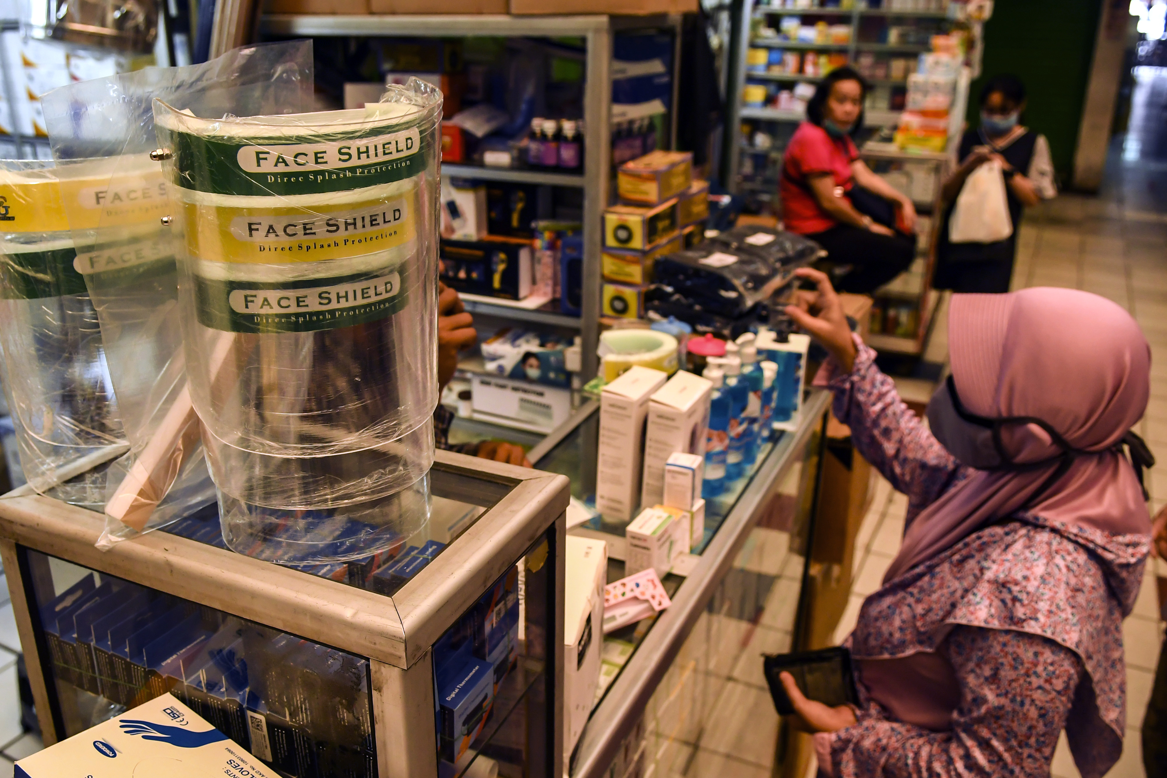 Pengunjung Pasar Pramuka membeli alat pelindung wajah.