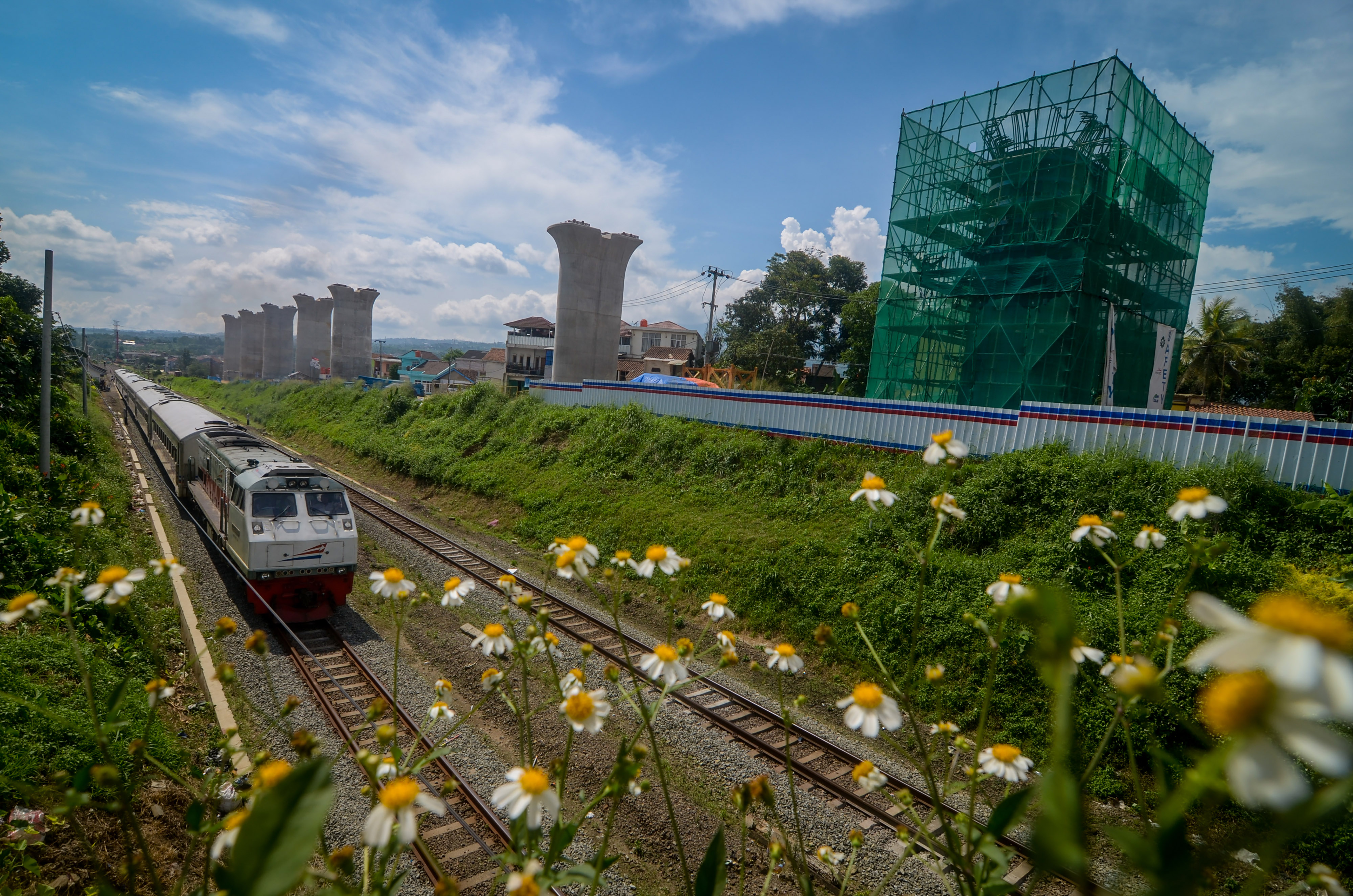 Kereta api melintas di samping proyek pembangunan jalur kereta cepat Jakarta-Bandung