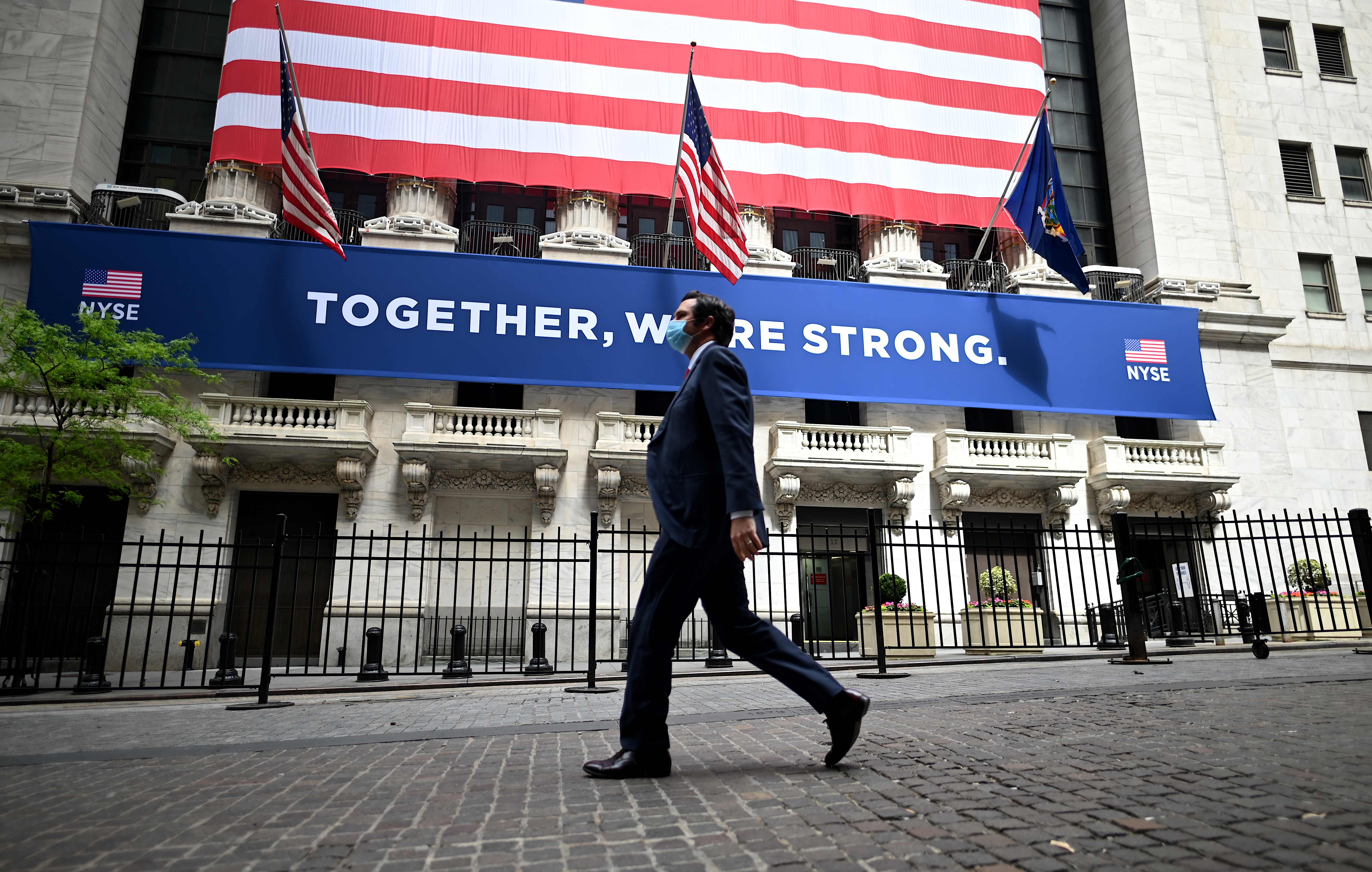 Orang berjalan di depan gedung The New York Stock Exchange (NYSE) Wall Street New York.