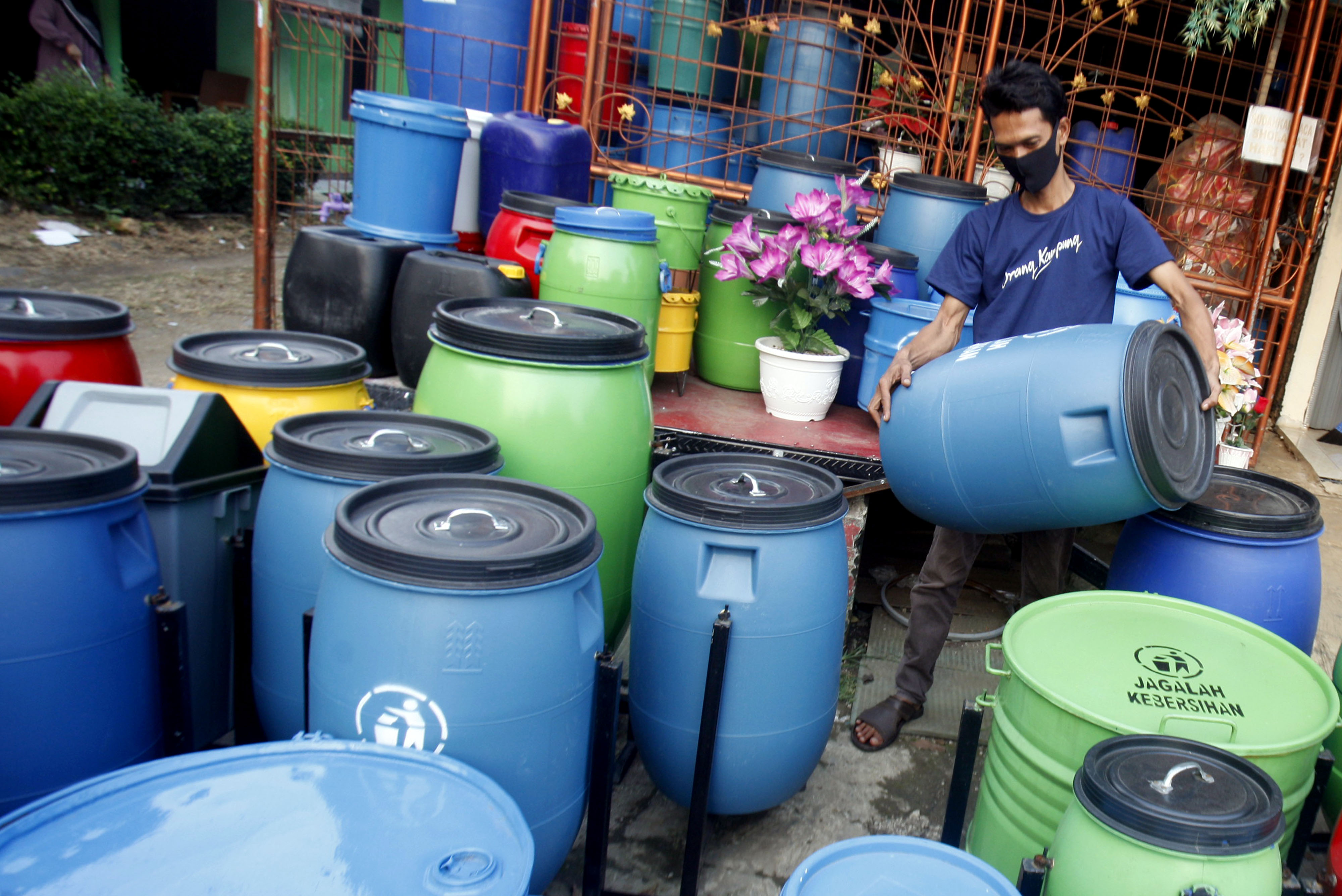 Perajin tempat sampah daur ulang yang memanfaatkan KUR sedang menata hasil karyanya