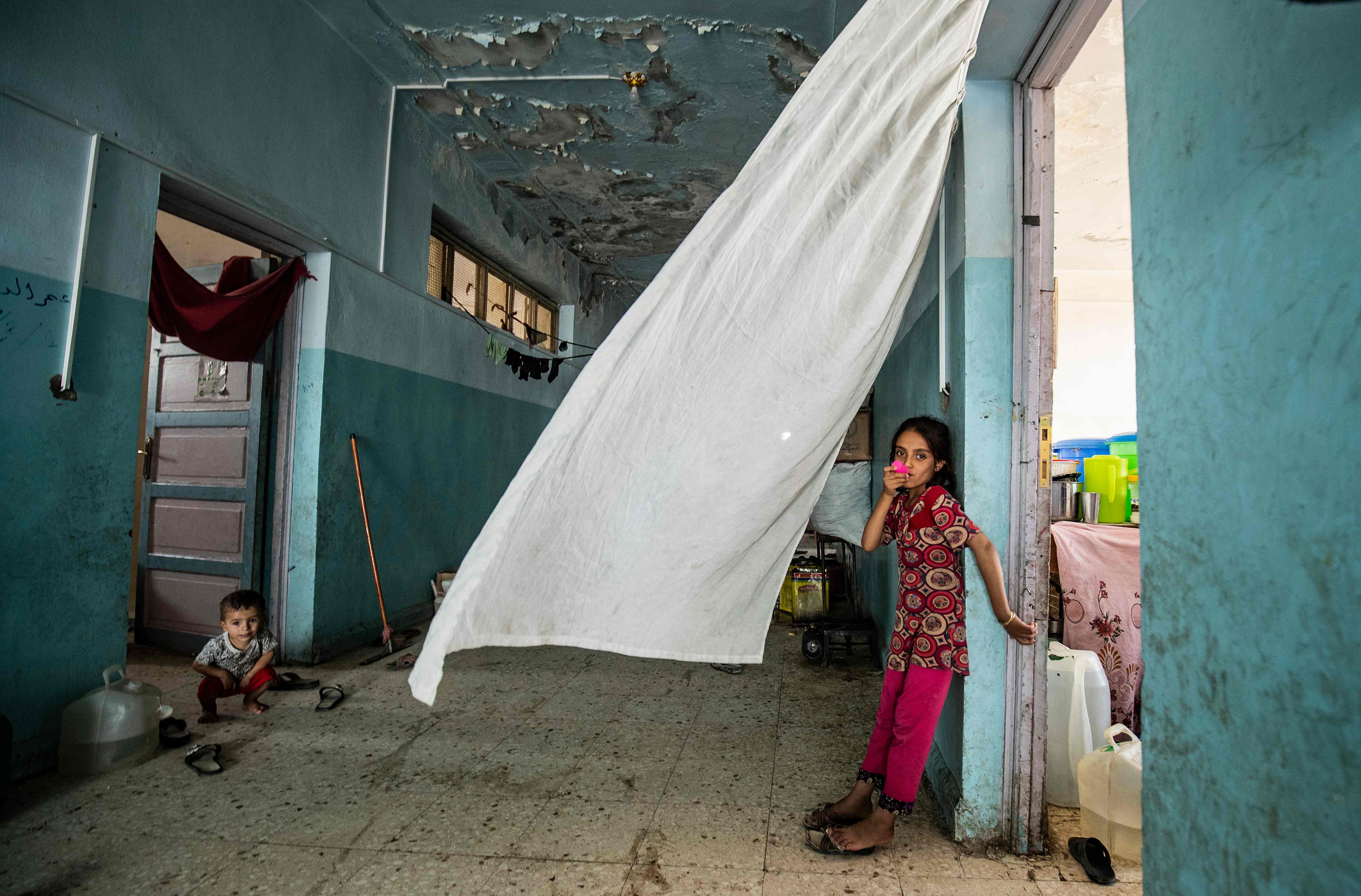 Seorang gadis berdiri di dekat pintu di lorong sebuah gedung sekolah tempat warga Suriah mengungsi dari Ras al-Ain yang dikuasai Turki.