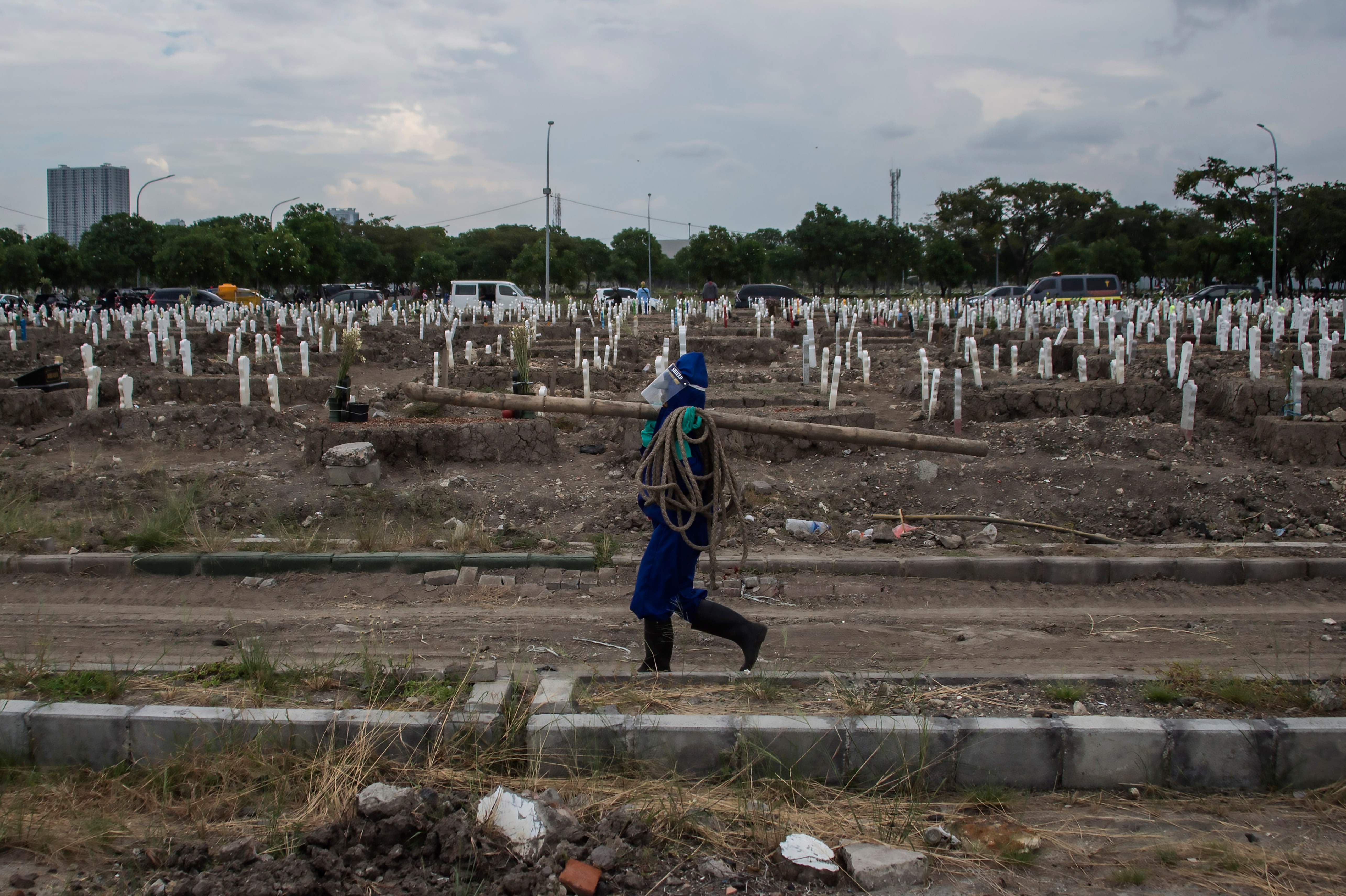 Seorang pekerja membawa peralatan di sebuah situs pemakaman untuk para korban covid-19 di pemakaman Keputih di Surabaya, Jatim, Rabu (15/7).