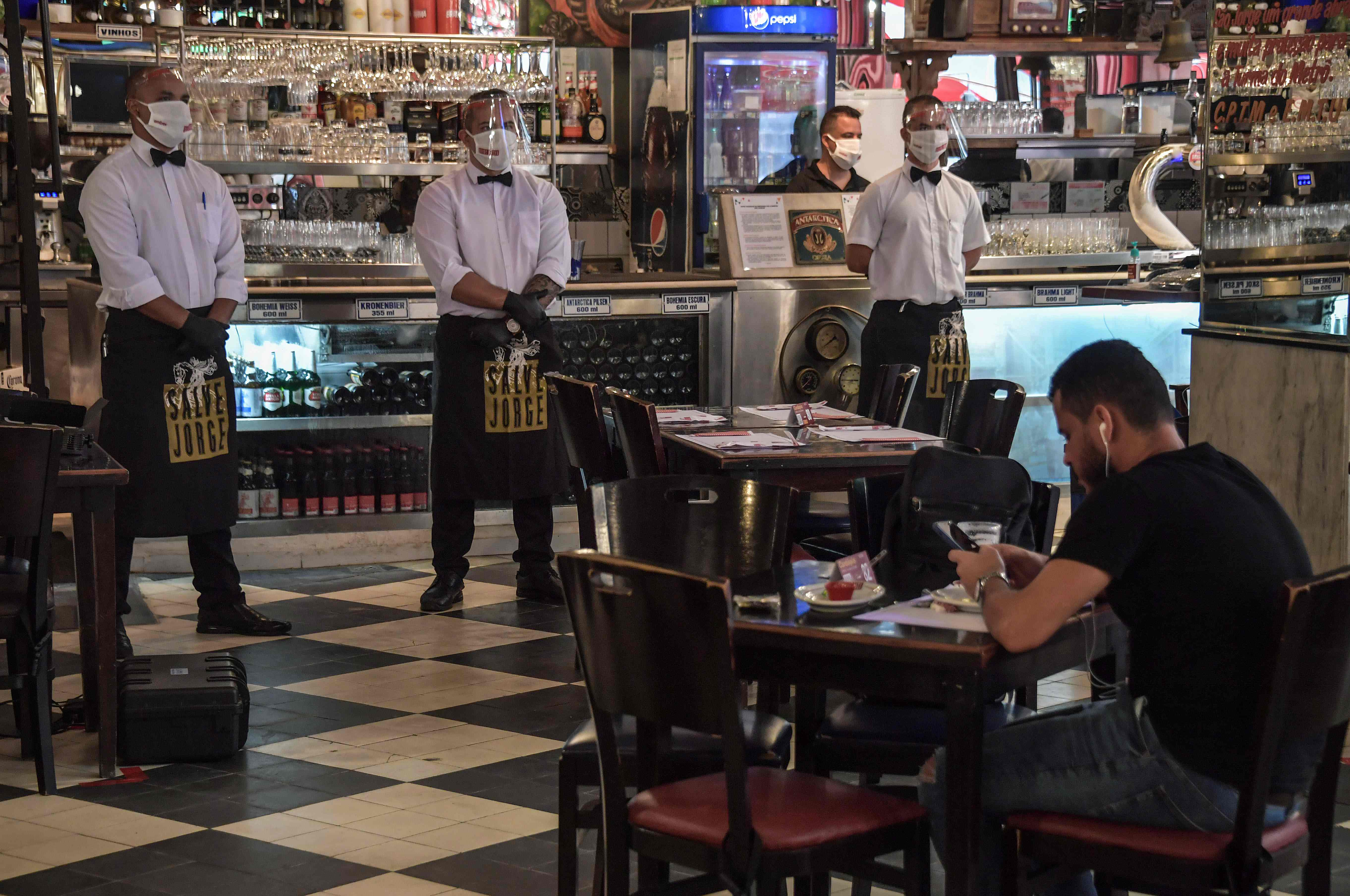 Seorang warga mengecek ponselnya saat makan di sebuah bar di Sao Paulo, Brasil.