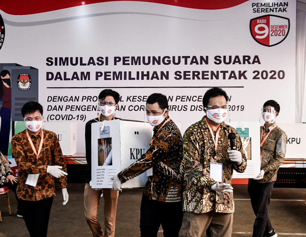 Petugas di TPS memakai masker dan face shield serta sarung tangan saat mengangkat kotak suara dalam simulasi pemungutan suara di Gedung KPU