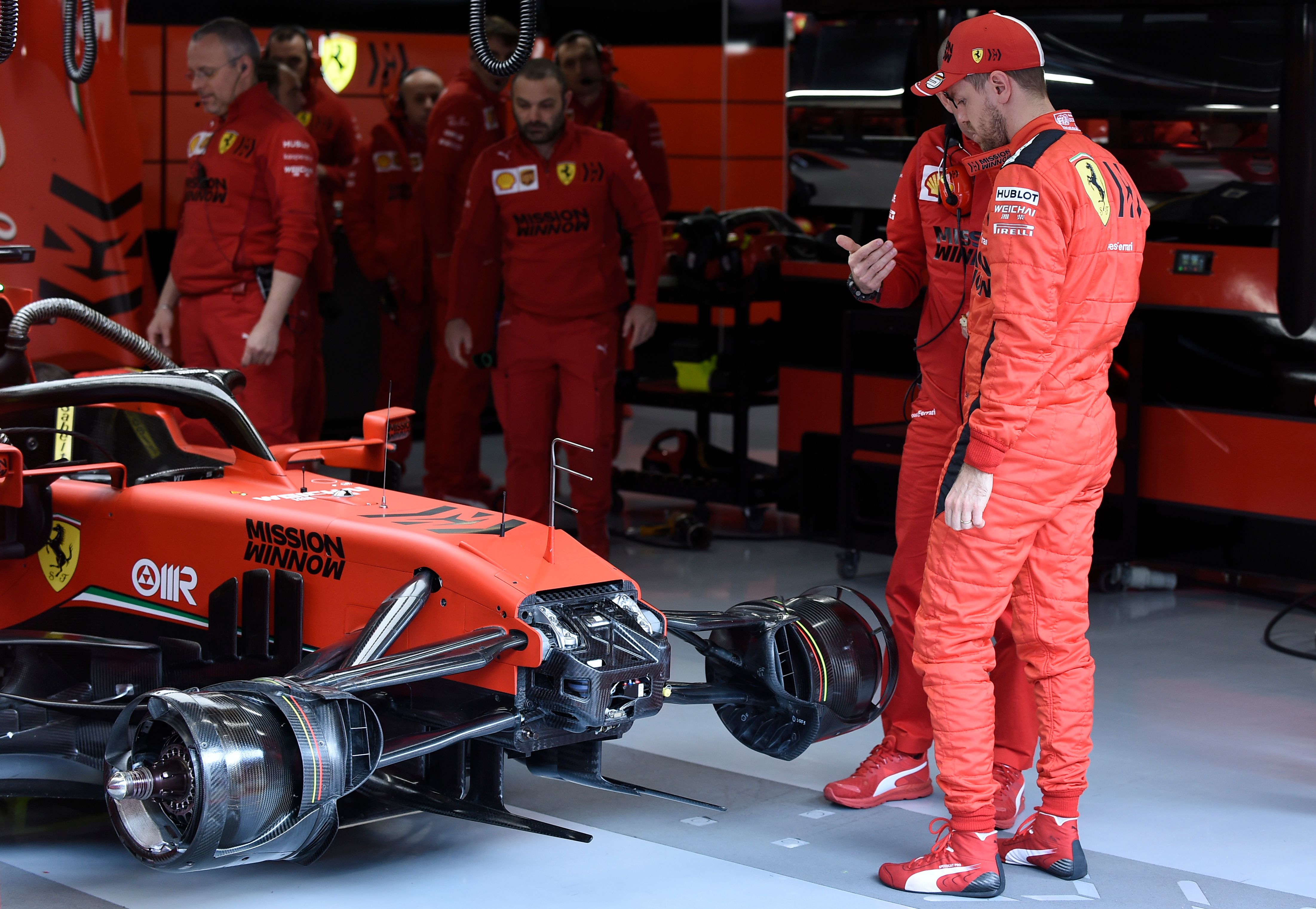 Pembalap Ferrari Sebastian Fettel (kanan) melihat mobilnya yang tengah ditangani mekanik di Barcelona, Spanyol, Kamis (27/2).