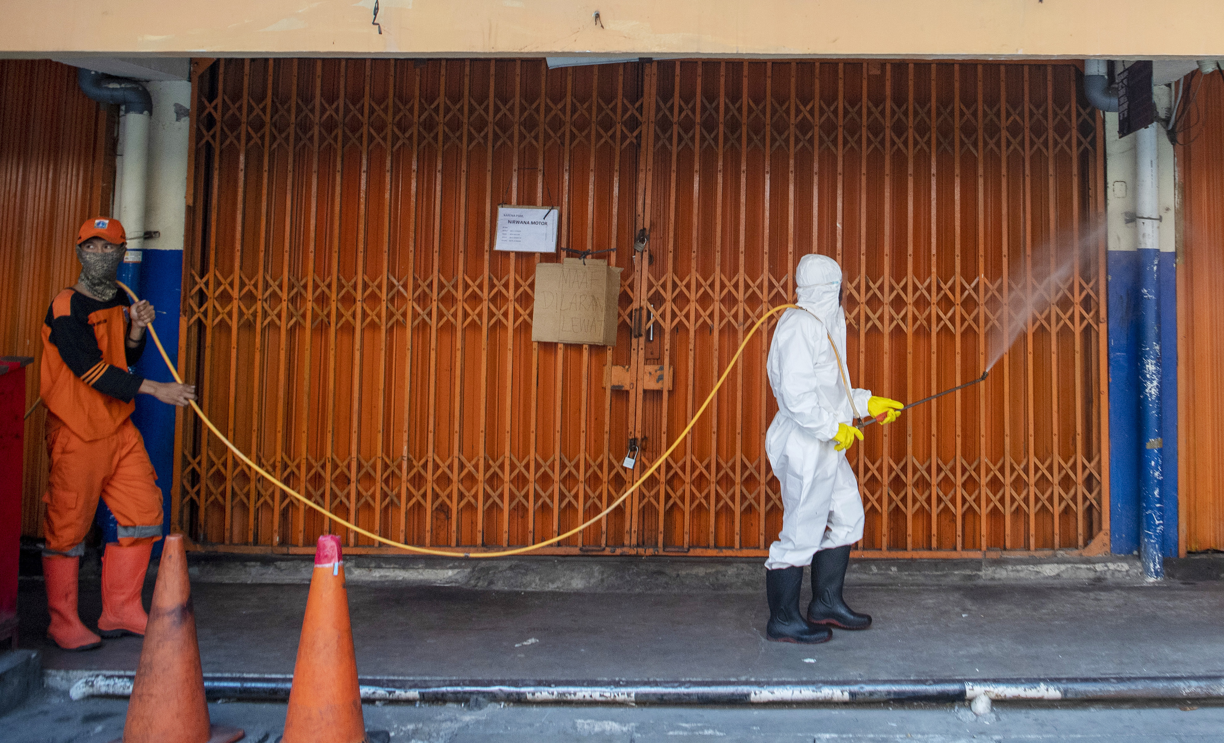 Petugas menyemprot disinfektan di pasar Asem Reges, Jakarta Barat usai salah seorang pedagang positif Covid-19