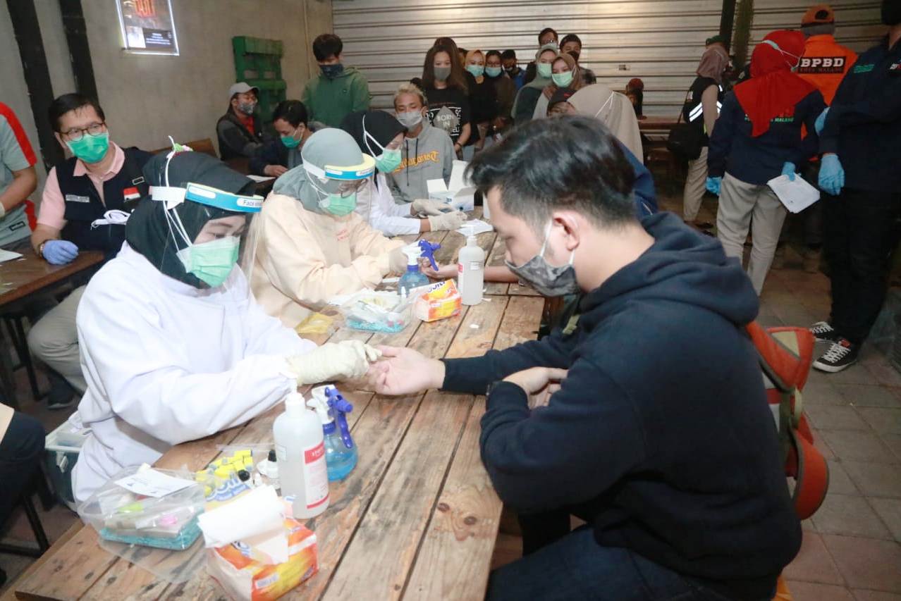 Petugas gabungan melakukan tes cepat pada pengelola pengunjung kafe saat operasi gabungan di Kota Malang, Sabtu (4/7) malam.