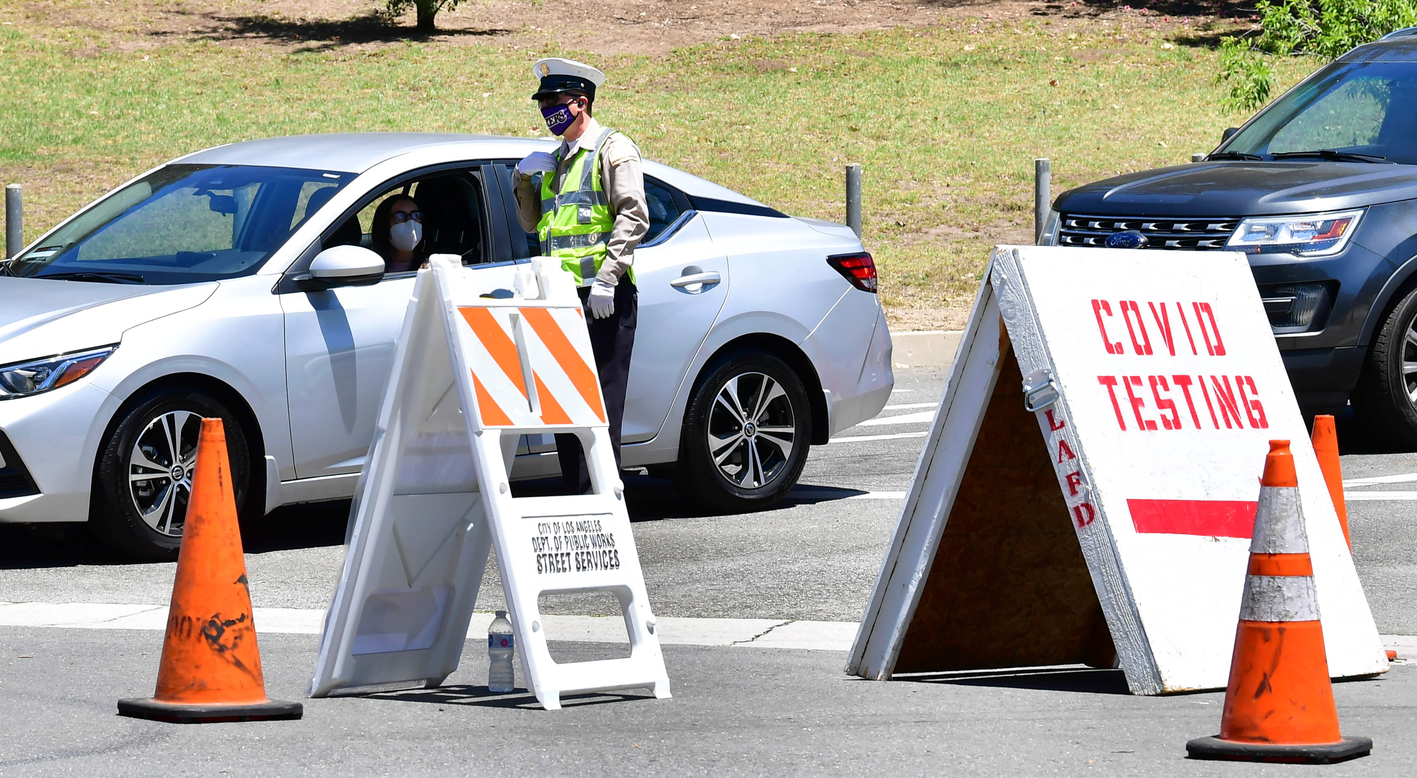 Petugas berbicara kepada pengemudi yang akan masuk ke Dodger Stadium, Los Angeles untuk  melakukan tes covid-19, Jumat (30/7/2020)