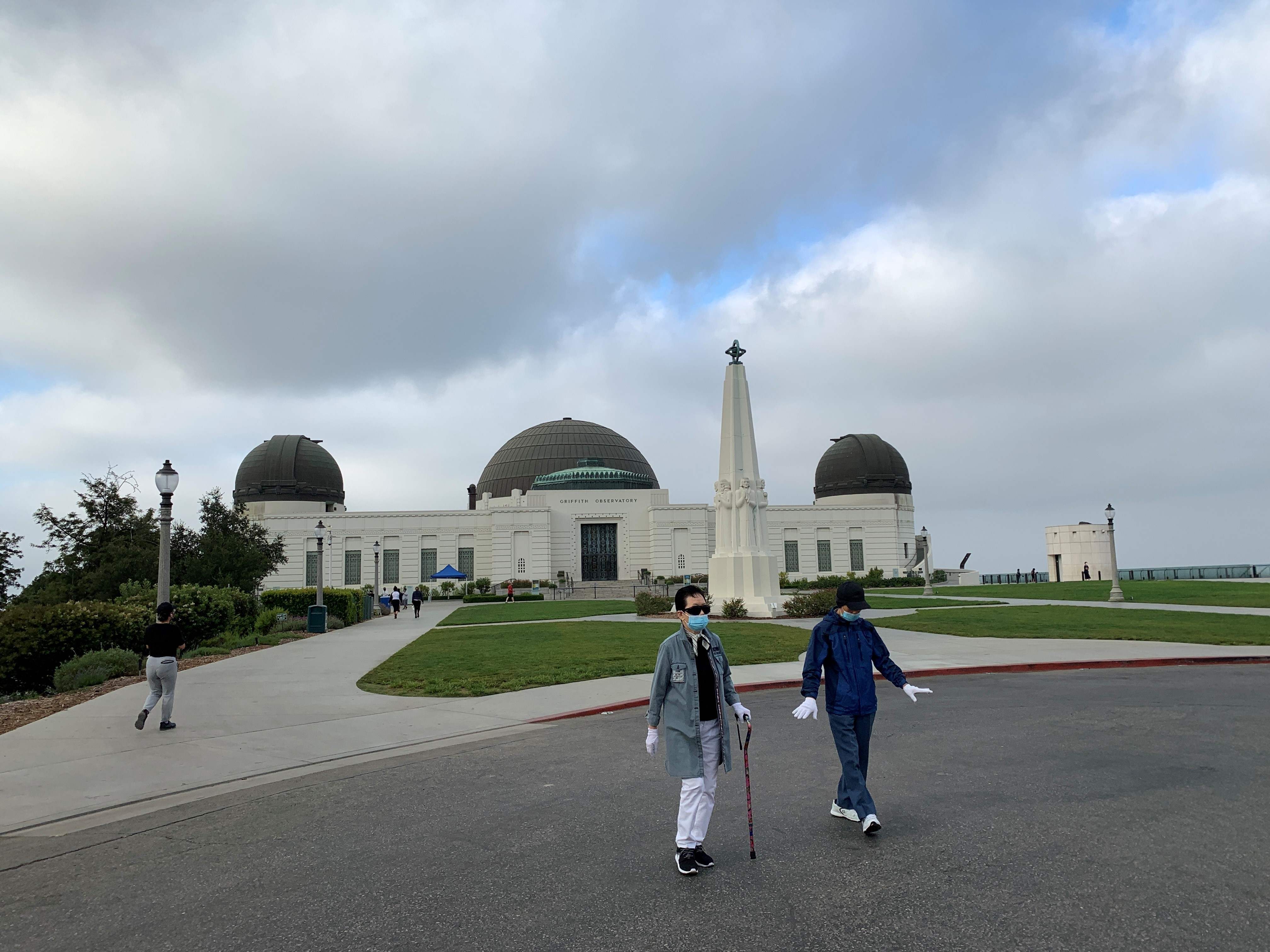 Dua warga mengenakan masker dan sarung tangan berjalan pagi di Griffith Park, Los Angeles, California, AS.