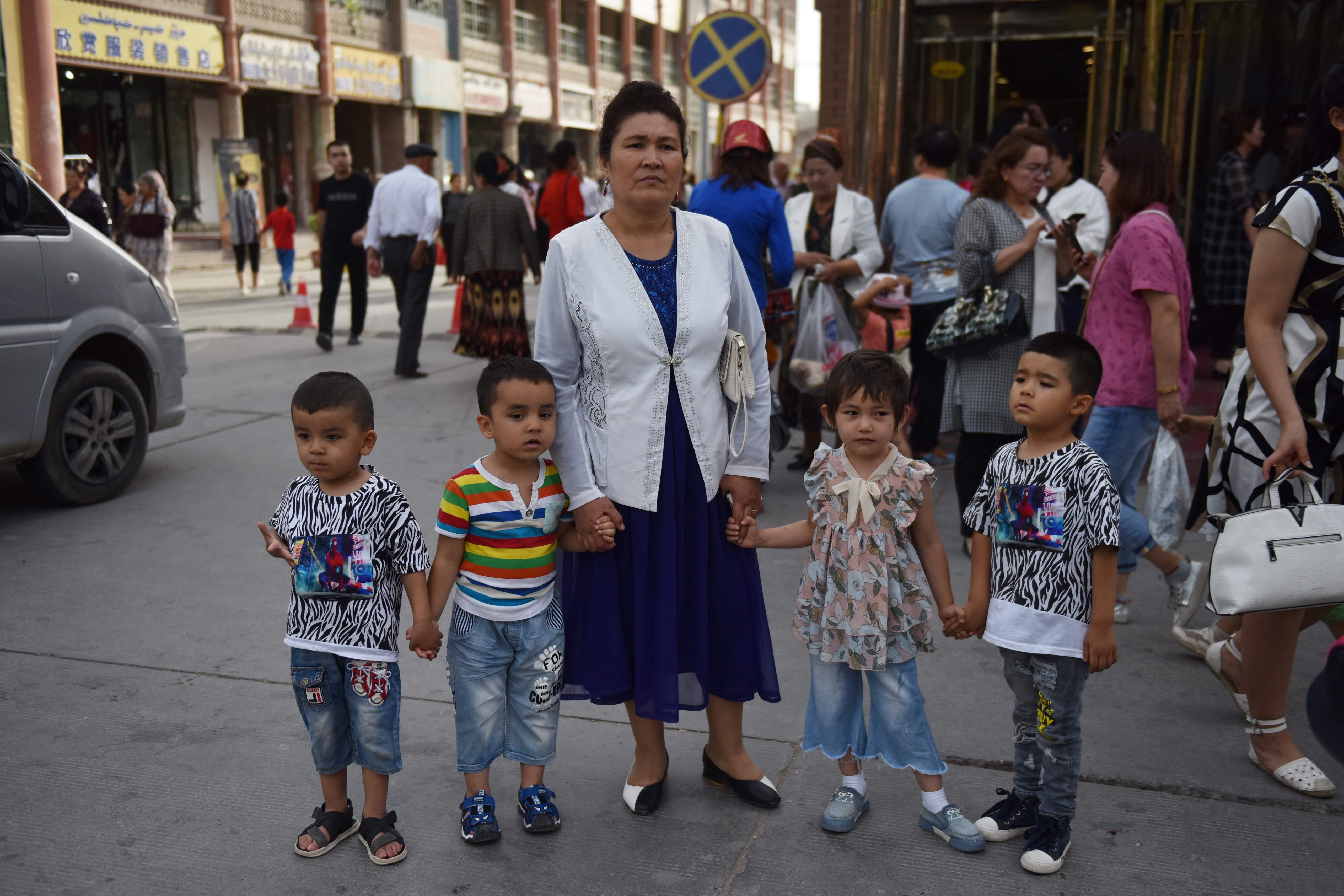 Seorang perempuan Uighur menggandeng sejumlah anak di Kashgar, Xinjiang, Tiongkok.