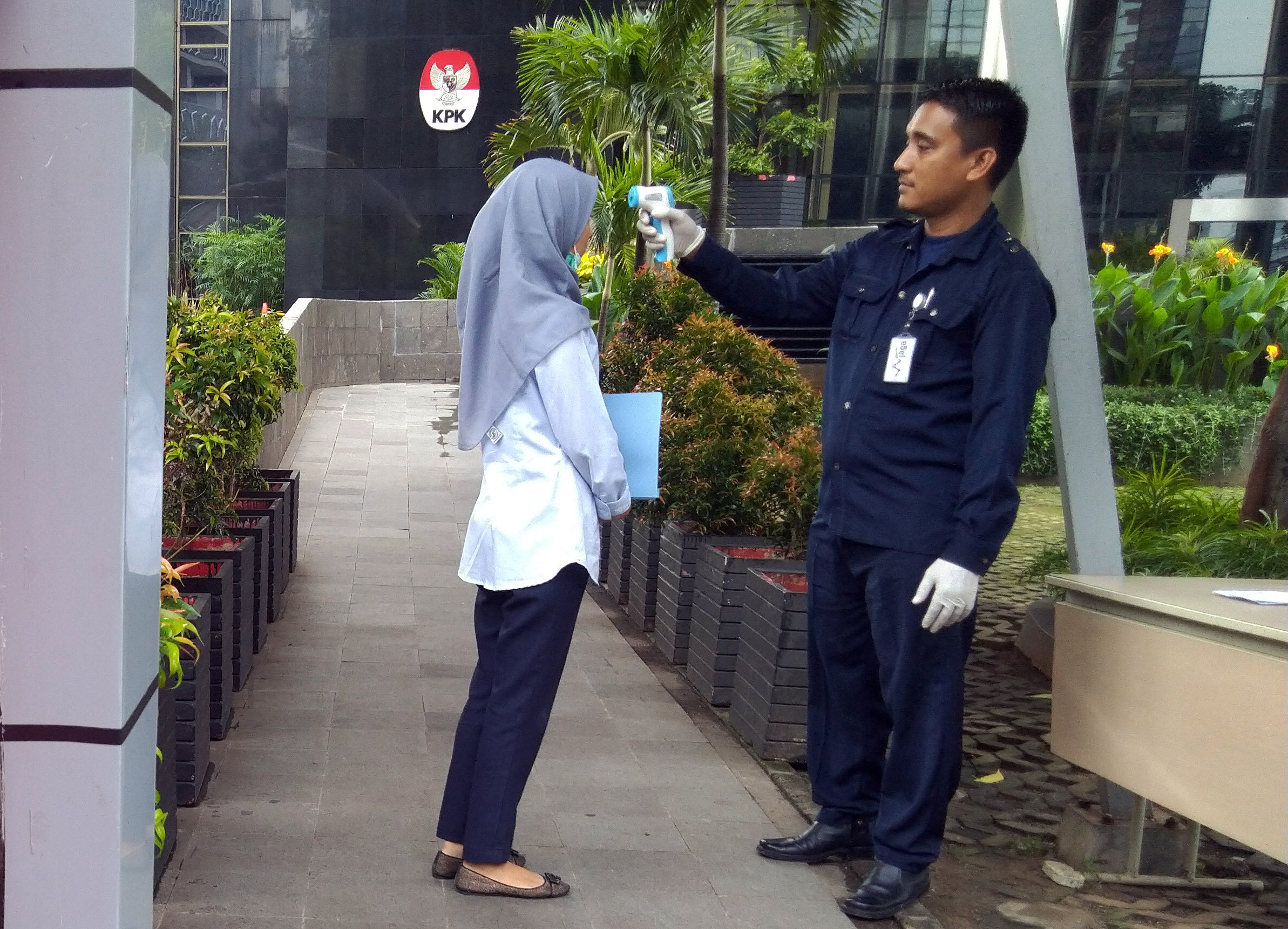 Petugas memeriksa suhu tubuh karyawan dan pengunjung KPK di Gedung Merah Putih KPK, Jakarta.