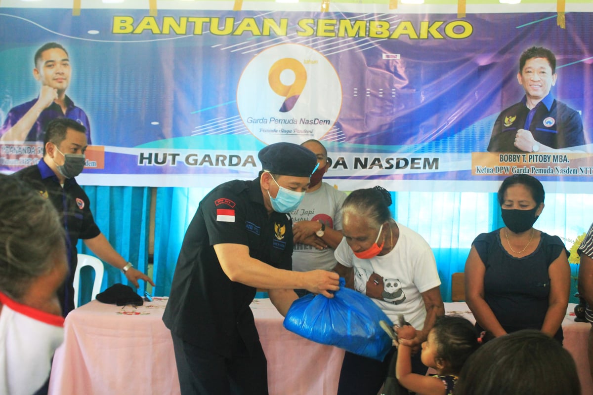 Ketua DPW Gerakan Pemuda (GP) NasDem NTT, Bobby Pitoby (dua dari kiri) menyerahkan paket sembako kepada warga di Kota Kupang, NTT.