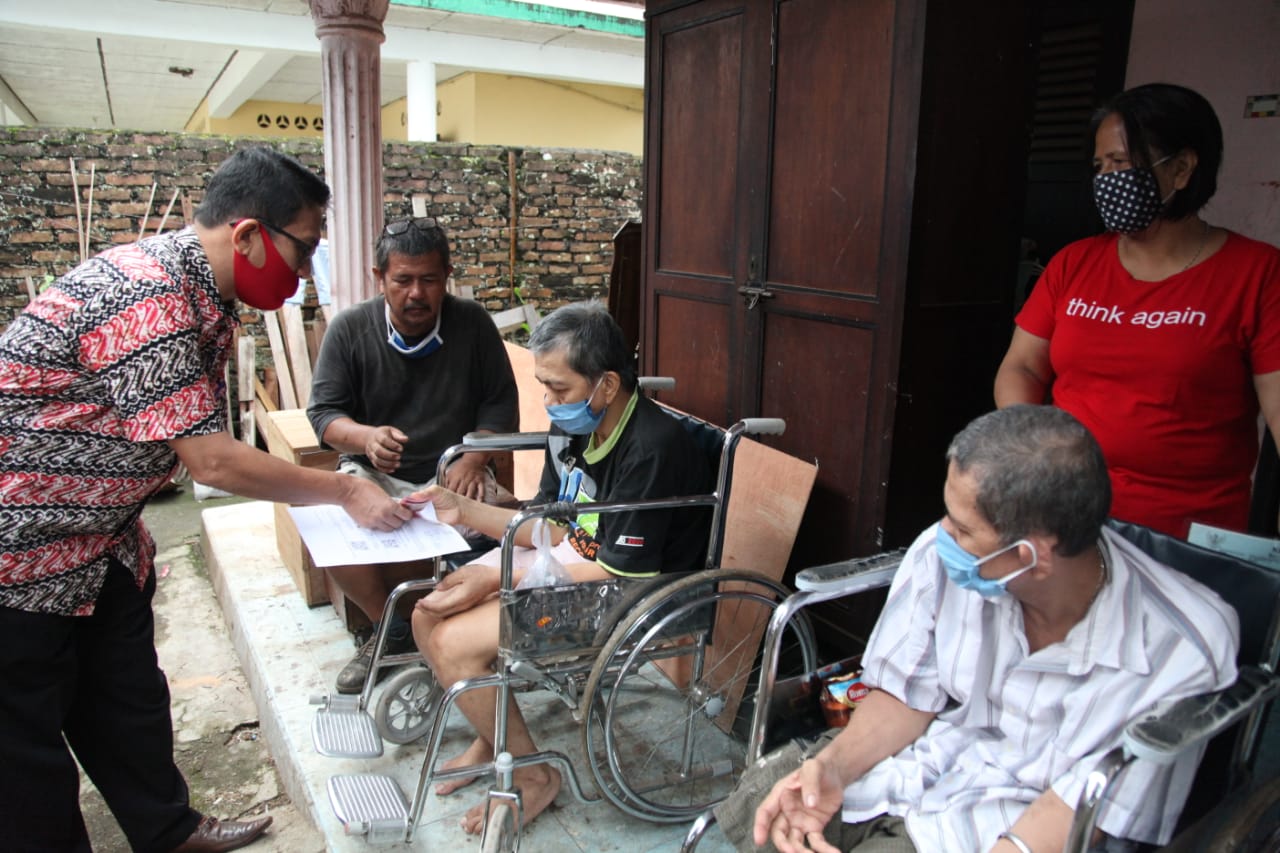Petugas Pos Indonesia Pemantang Siantar mengantarkan BST ke rumah penyandang disabilitas.
