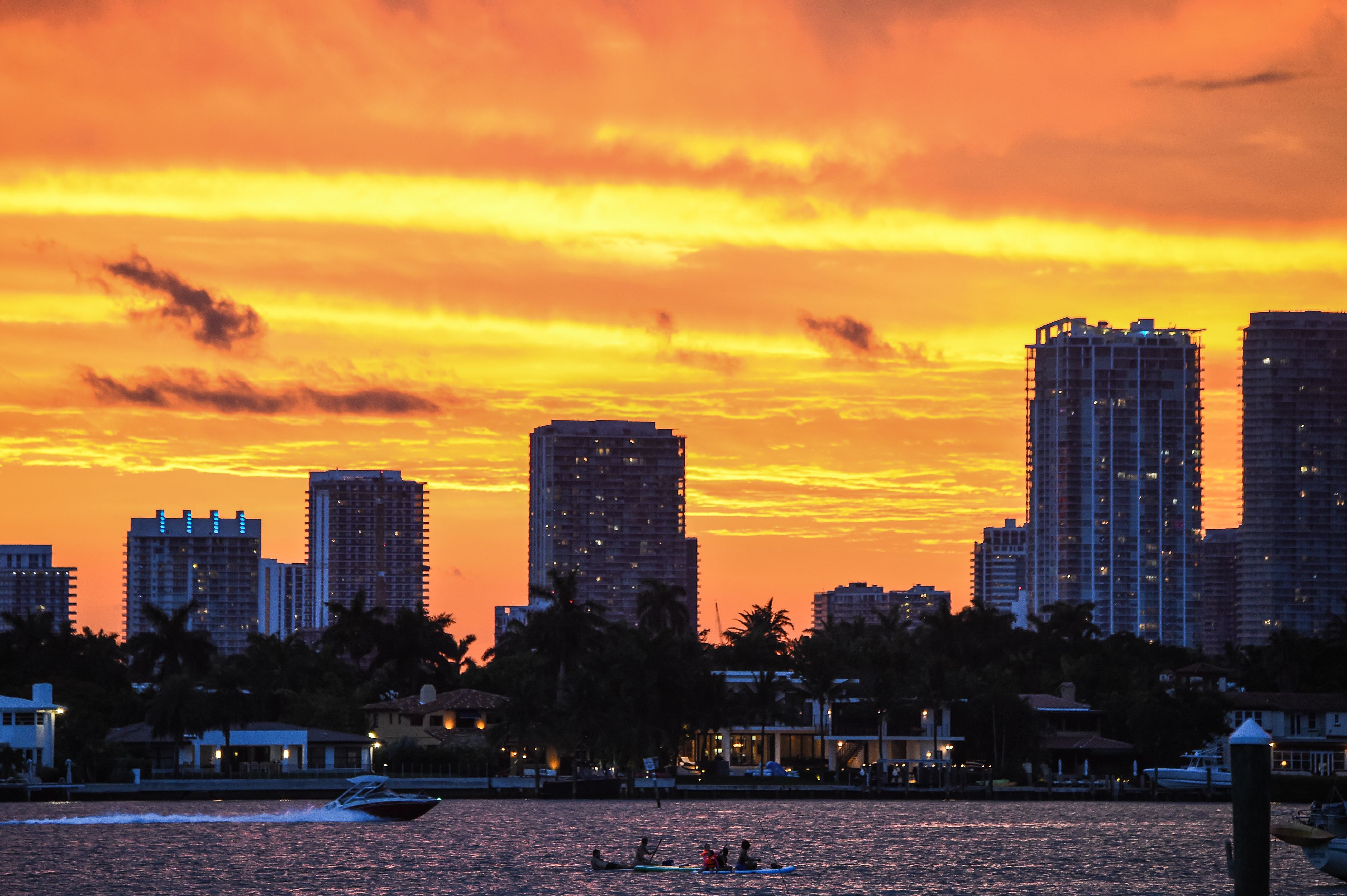 Orang-orang terlihat berkayak saat matahari terbenam di latar belakang di South Bay, Miami Beach, Florida, Selasa (14/7).