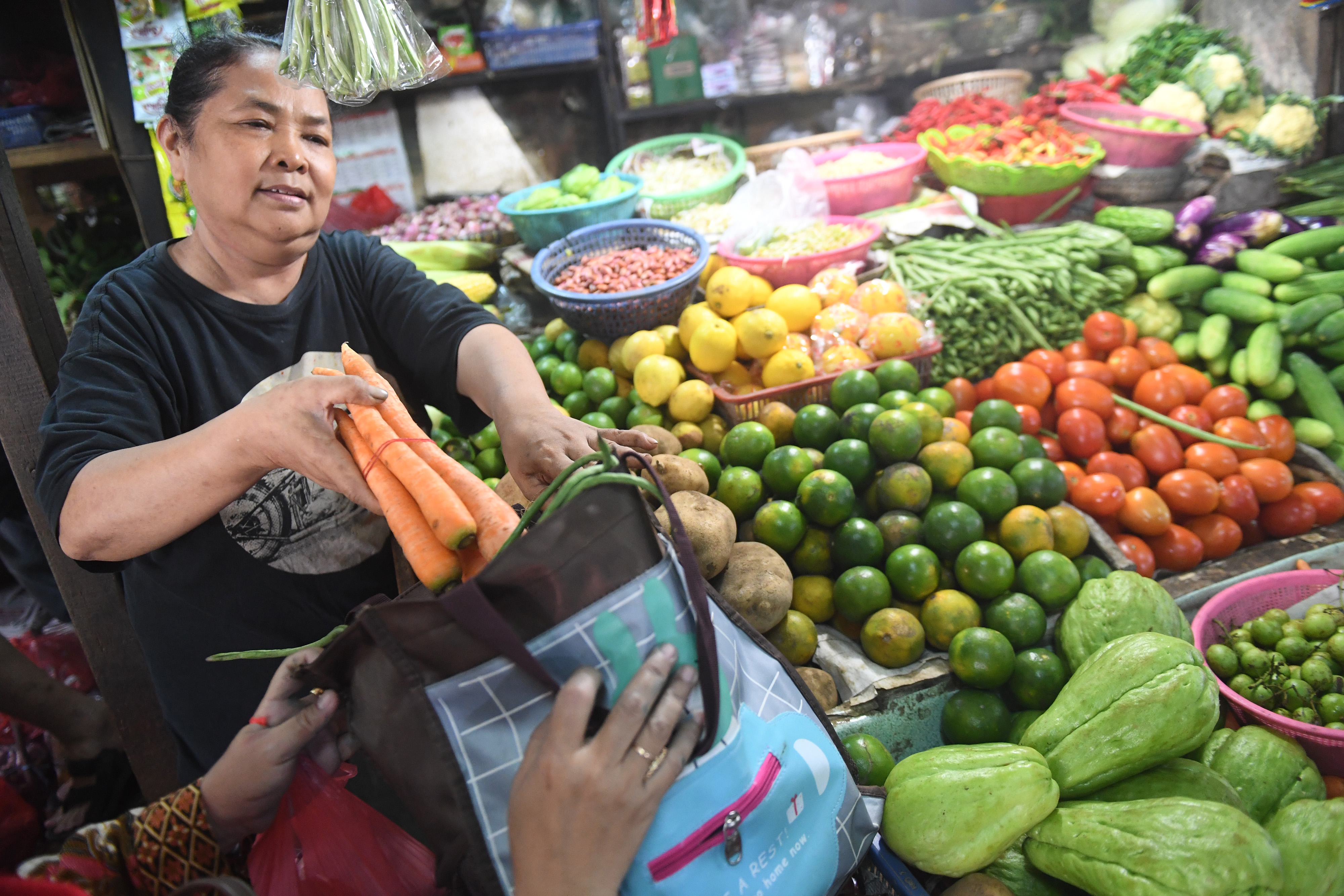  Pedagang memasukkan belanjaan ke dalam tas belanjaan saat bertransaksi di Pasar Tebet Barat Jakarta
