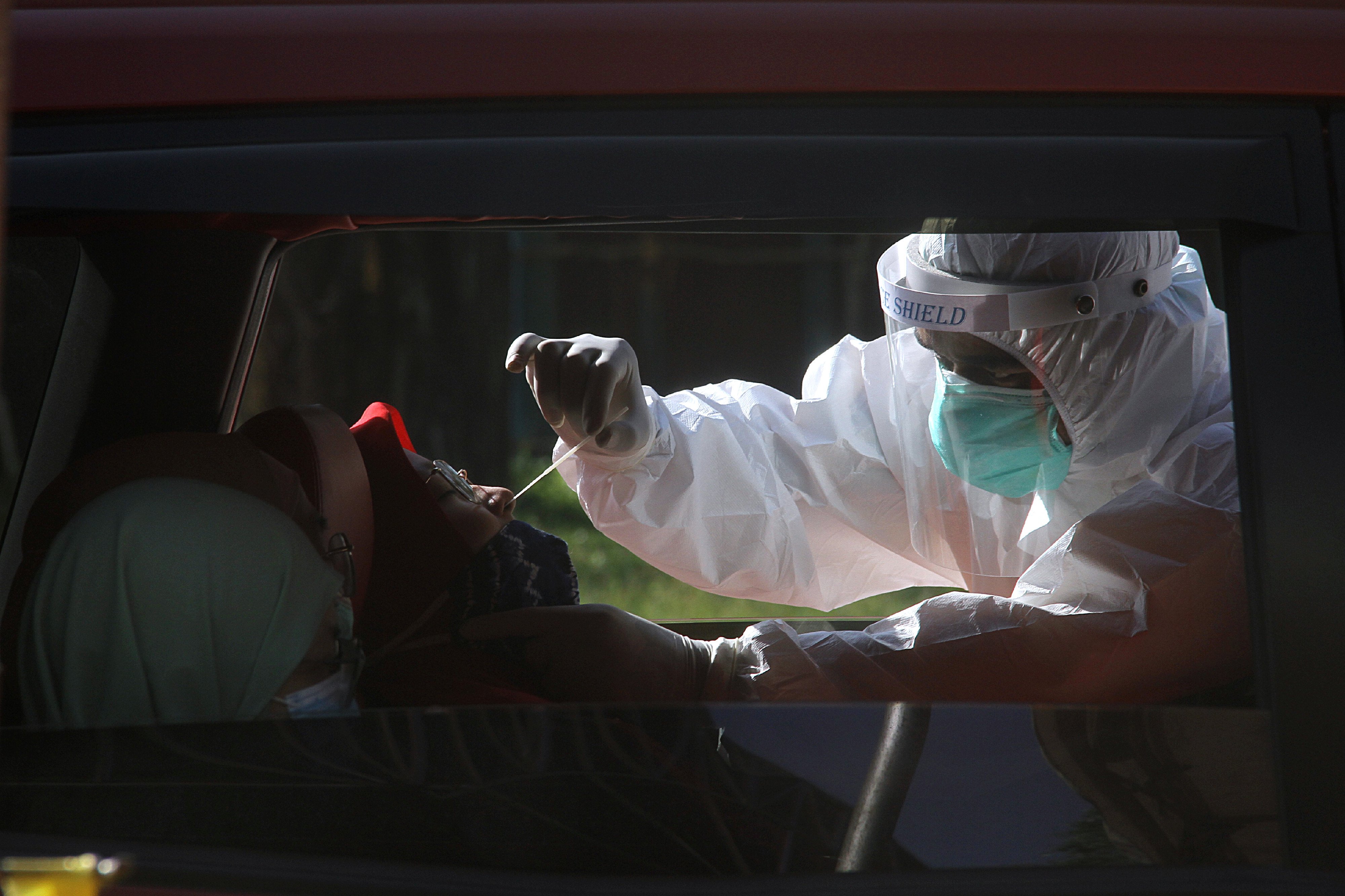 Petugas kesehatan mengambil sampel lendir warga saat tes usap drive-thru di Jalan Jendral Sudirman Banjarmasin, Kalsel, Rabu (24/6).