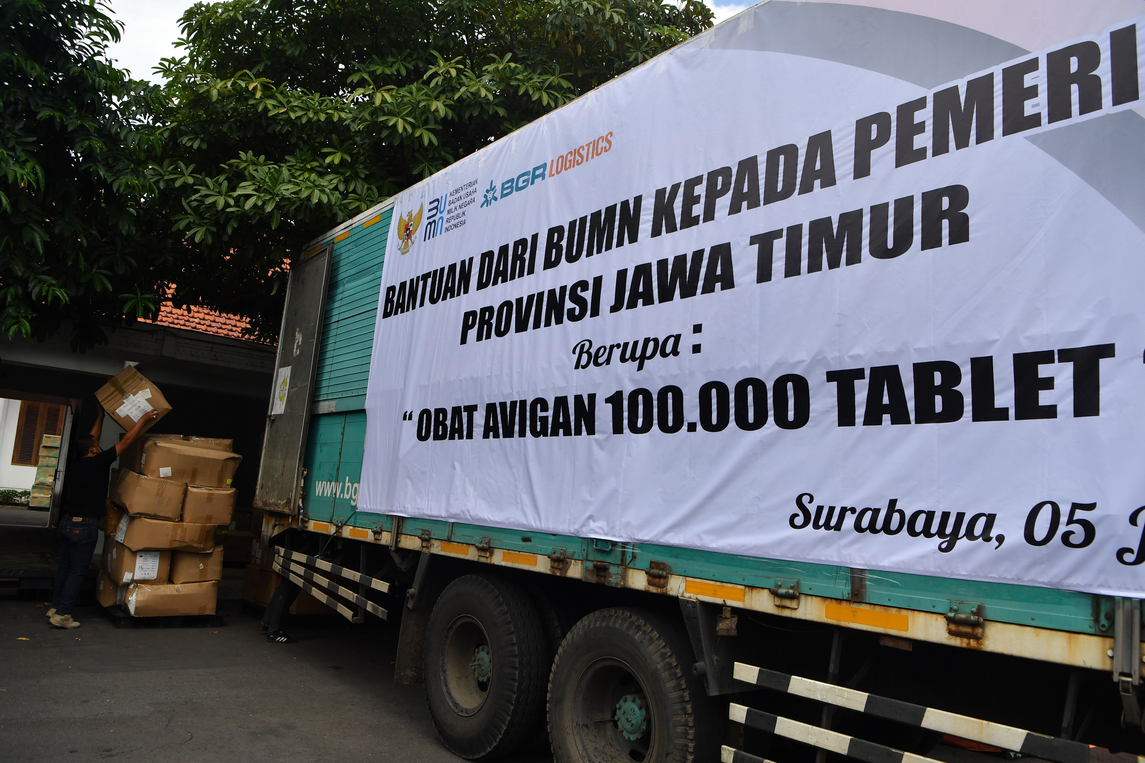 Pekerja menurunkan kardus yang berisi obat Avigan bantuan Kementerian BUMN di halaman Gedung Negara Grahadi, Surabaya, Jawa Timur, Minggu