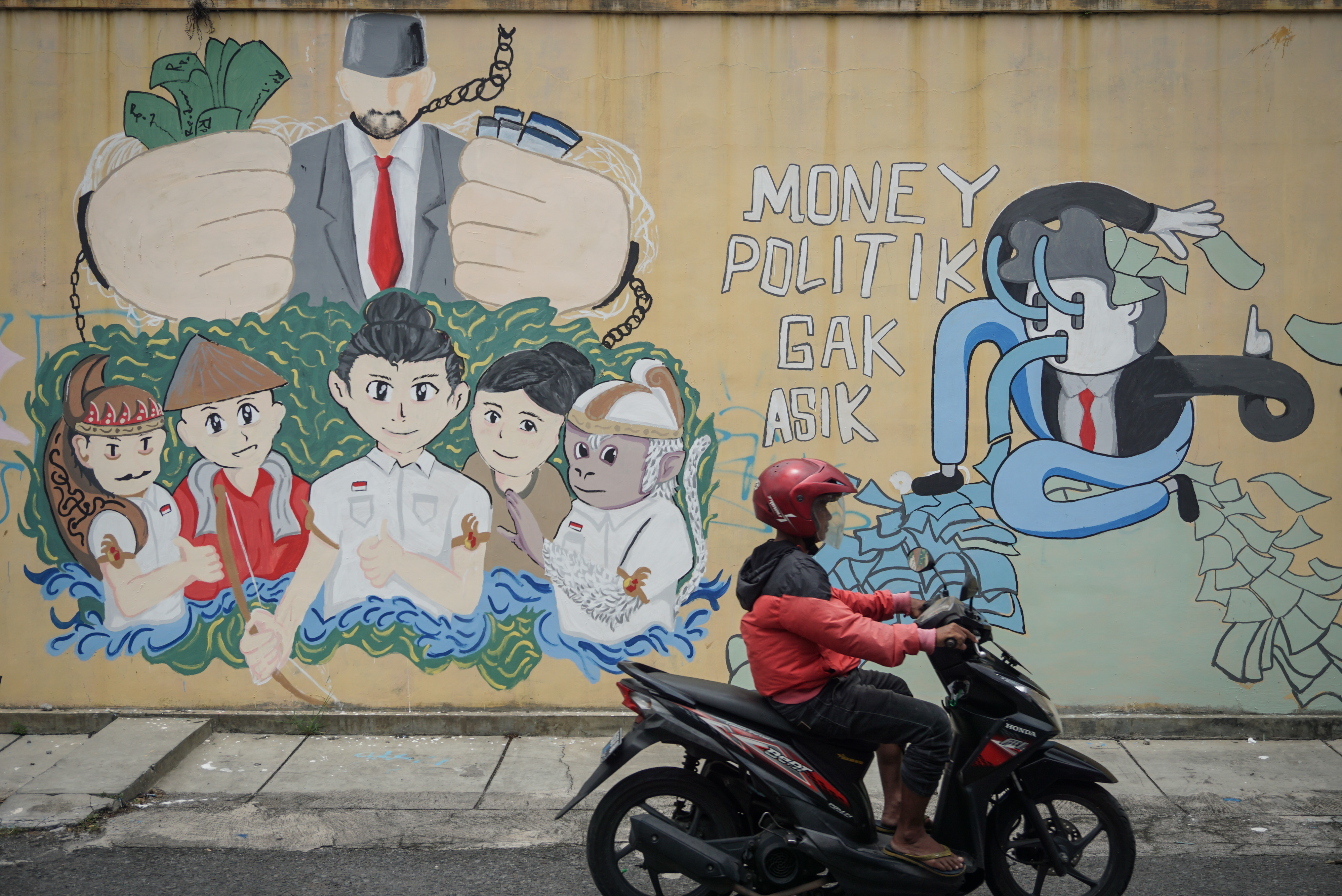 MURAL ANTI POLITIK UANG: Warga melintas di depan mural bertema antipolitik uang di kampung Sondakan, Laweyan, Solo, Jawa Tengah.