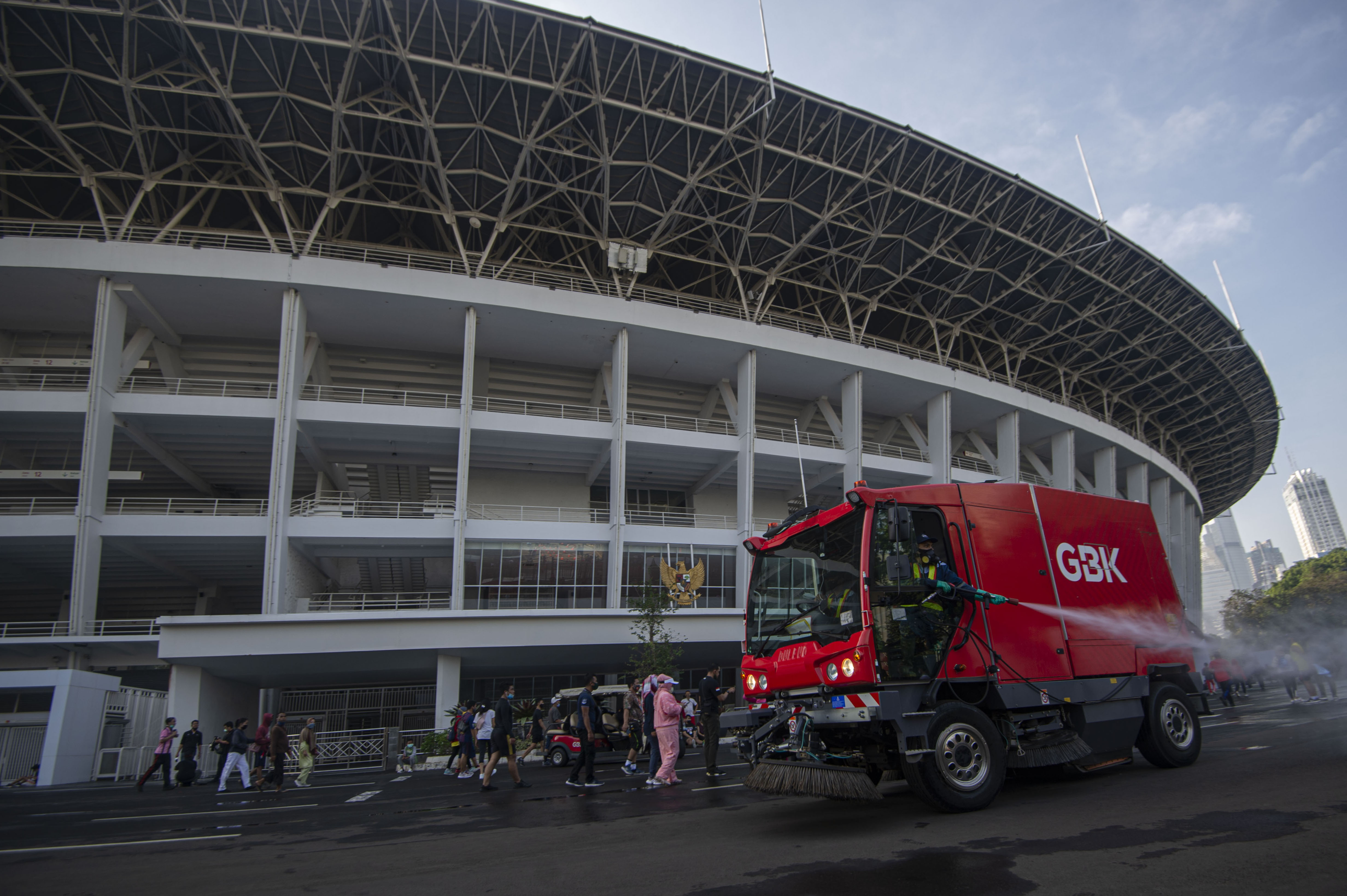 etugas menyemprotkan cairan disinfektan di kawasan 'ring road' Stadion Utama Gelora Bung Karno di Senayan (21/6/2020)
