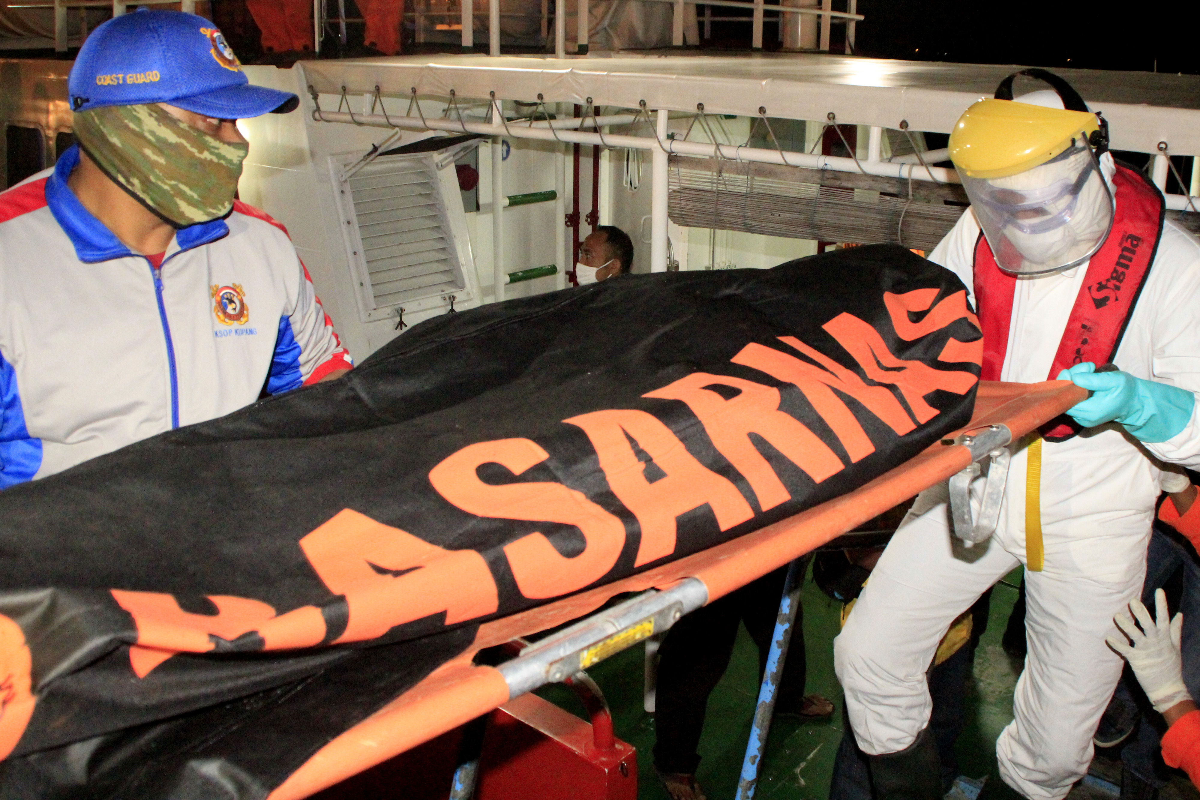 Petugas mengenakan APD lengkap membawa jenazah korban kapal tenggelam di Pelabuhan Tenau Kupang, NTT, Minggu (5/07/2020). 