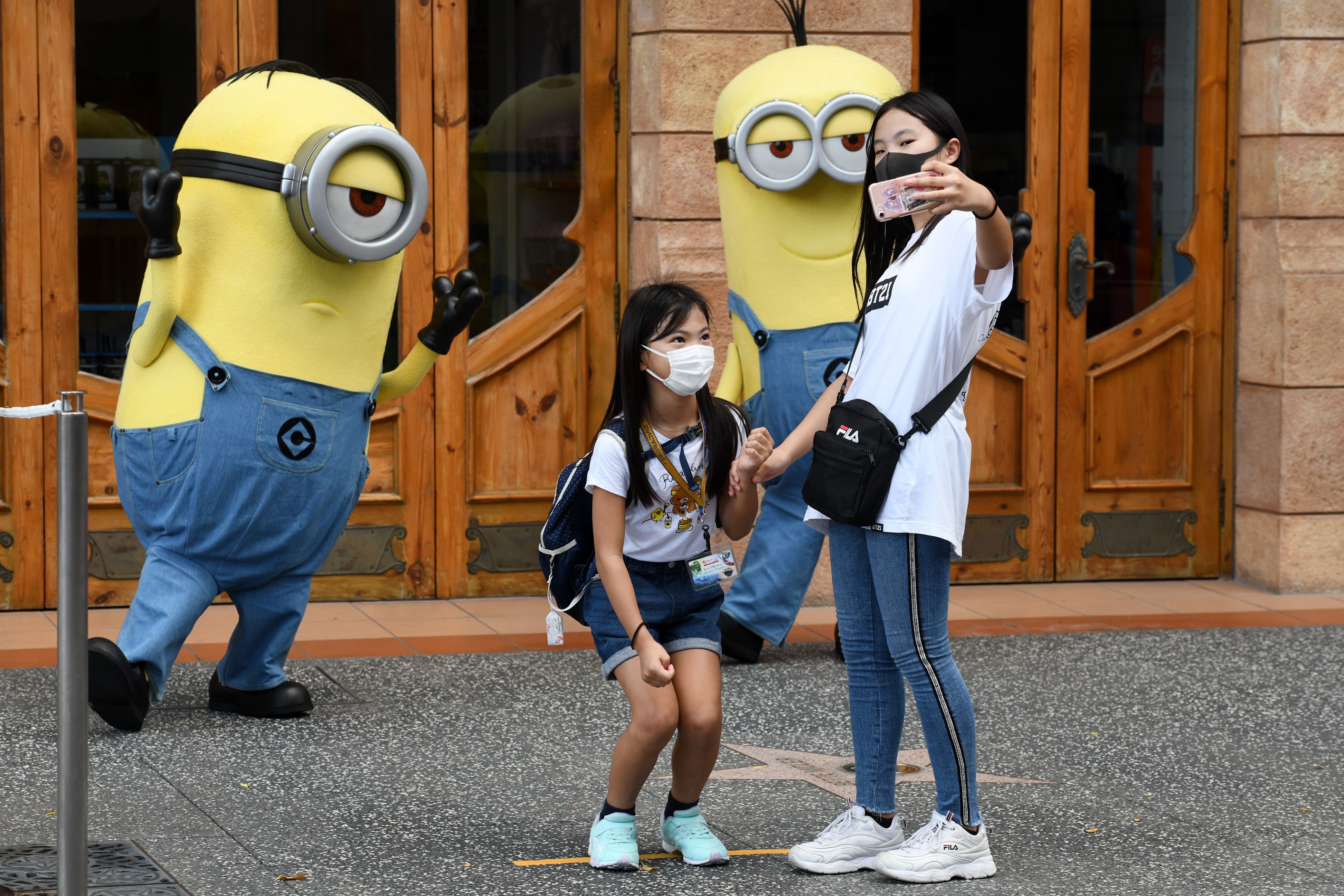 Dua pengunjung berpose di Universal Studio Singapura yang dibuka kembali setelah sempat ditutup karena pandemi covid-19.