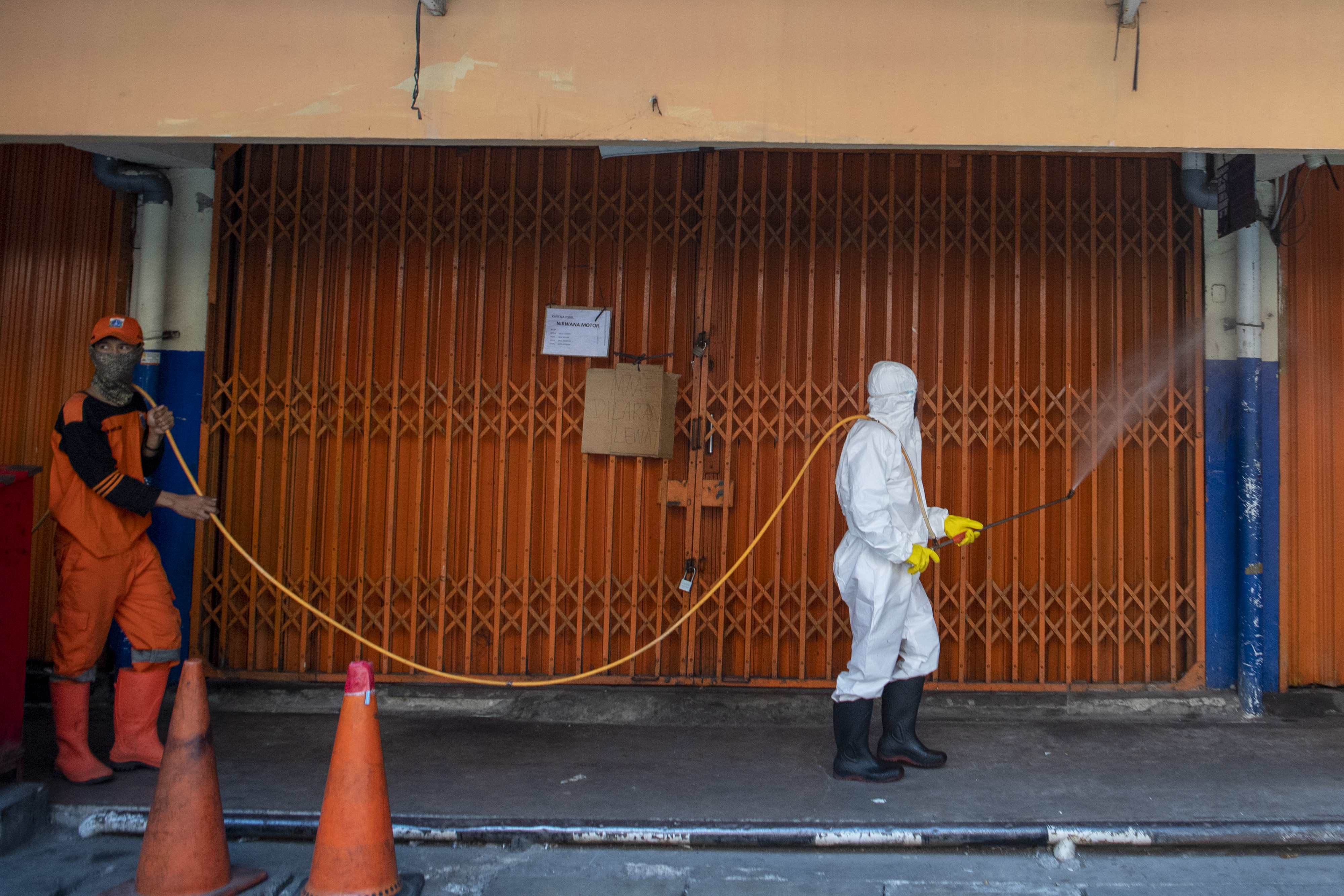 Petugas menyemprotkan cairan disinfektan di Pasar Asem Reges, Jakarta, menyusul adanya pedagang positif covid-19.