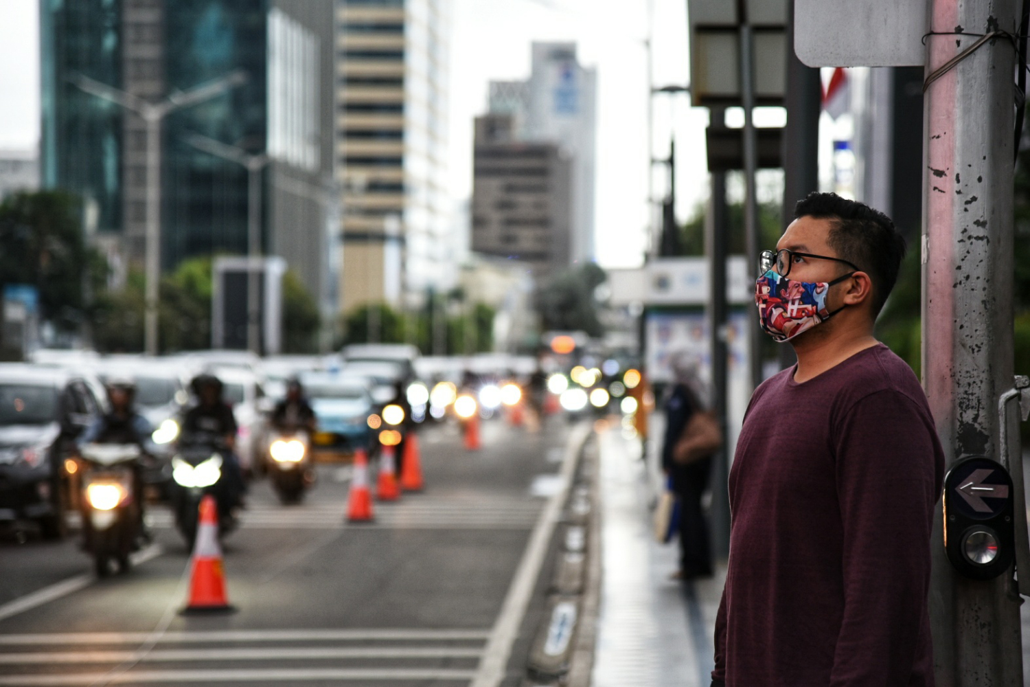 Seorang warga mengenakan masker sebagai bagian dari protokol kesehatan akan menyebrang jalan MH. Thamrin, Jakarta.