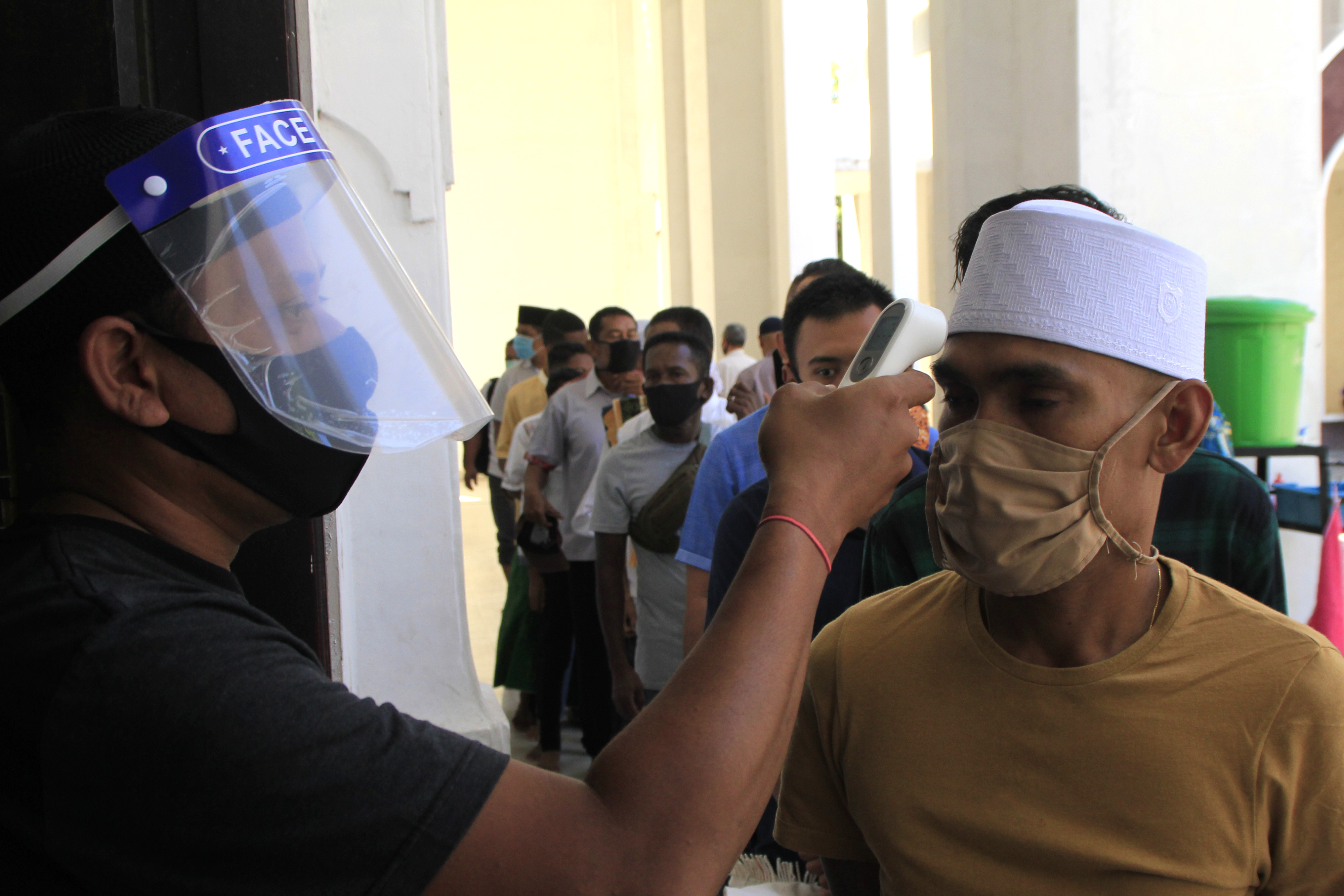 Petugas masjid memeriksa suhu tubuh umat Islam yang hendak menunaikan salat jumat di Masjid Raya Nurussa'adah, Kupang, NTT, Jumat (5/6).
