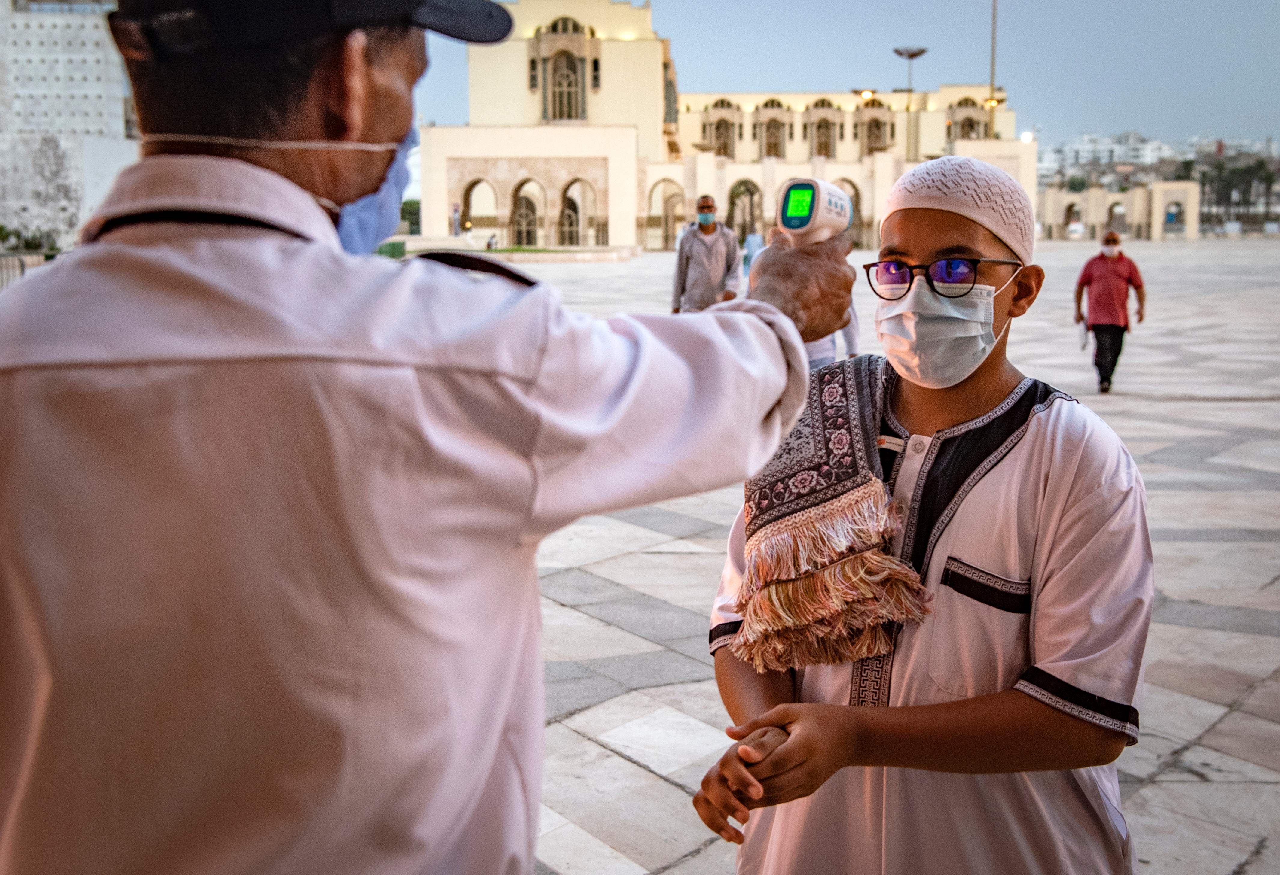 Petugas mengukur suhu tubuh warga yang akan salat di Hasan II di Casablanca, Maroko.