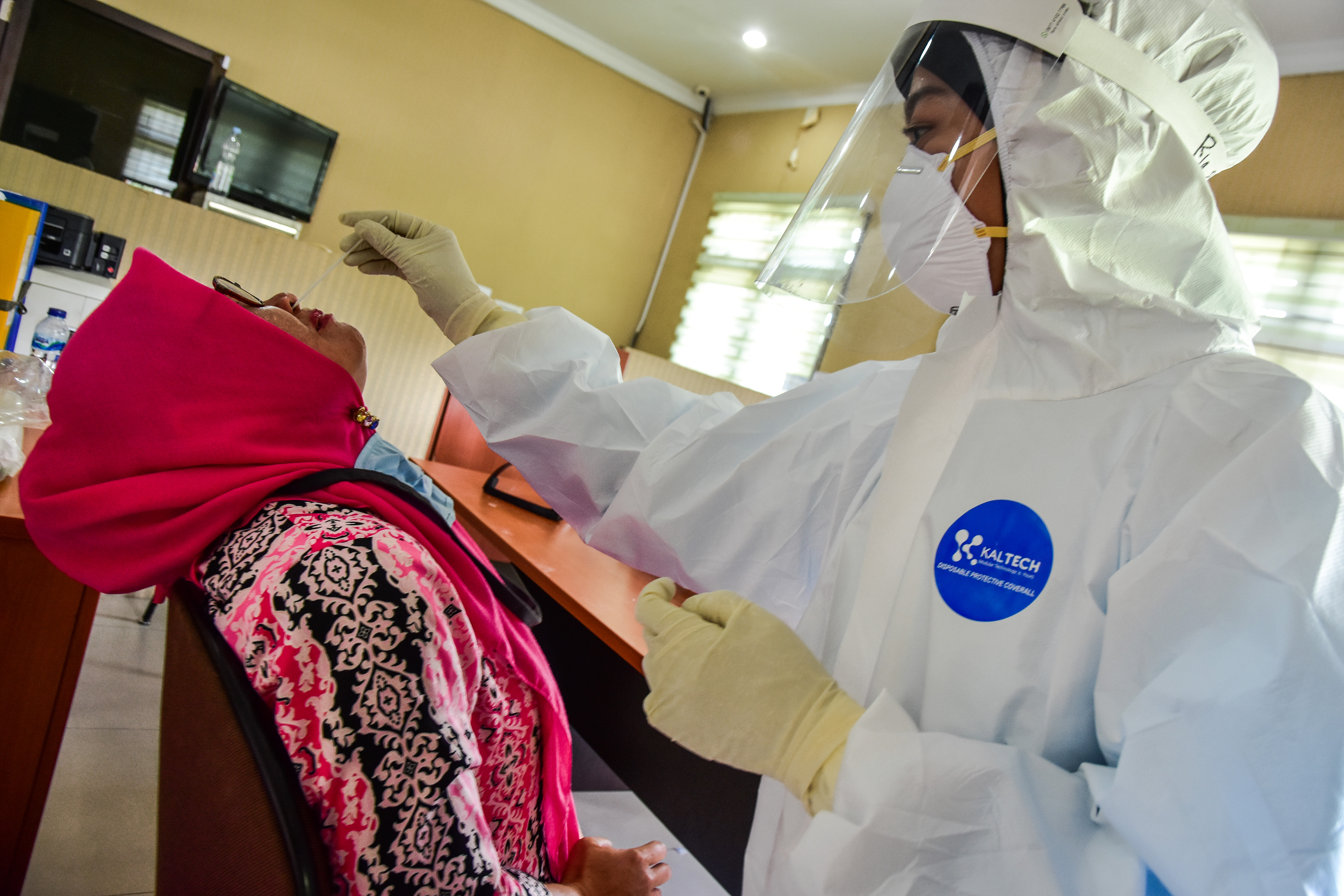  Seorang tenaga kesehatan (Nakes) mengenakan alat pelindung diri lengkap melakukan uji usap massal di kantor pemerintahan Provinsi Riau.