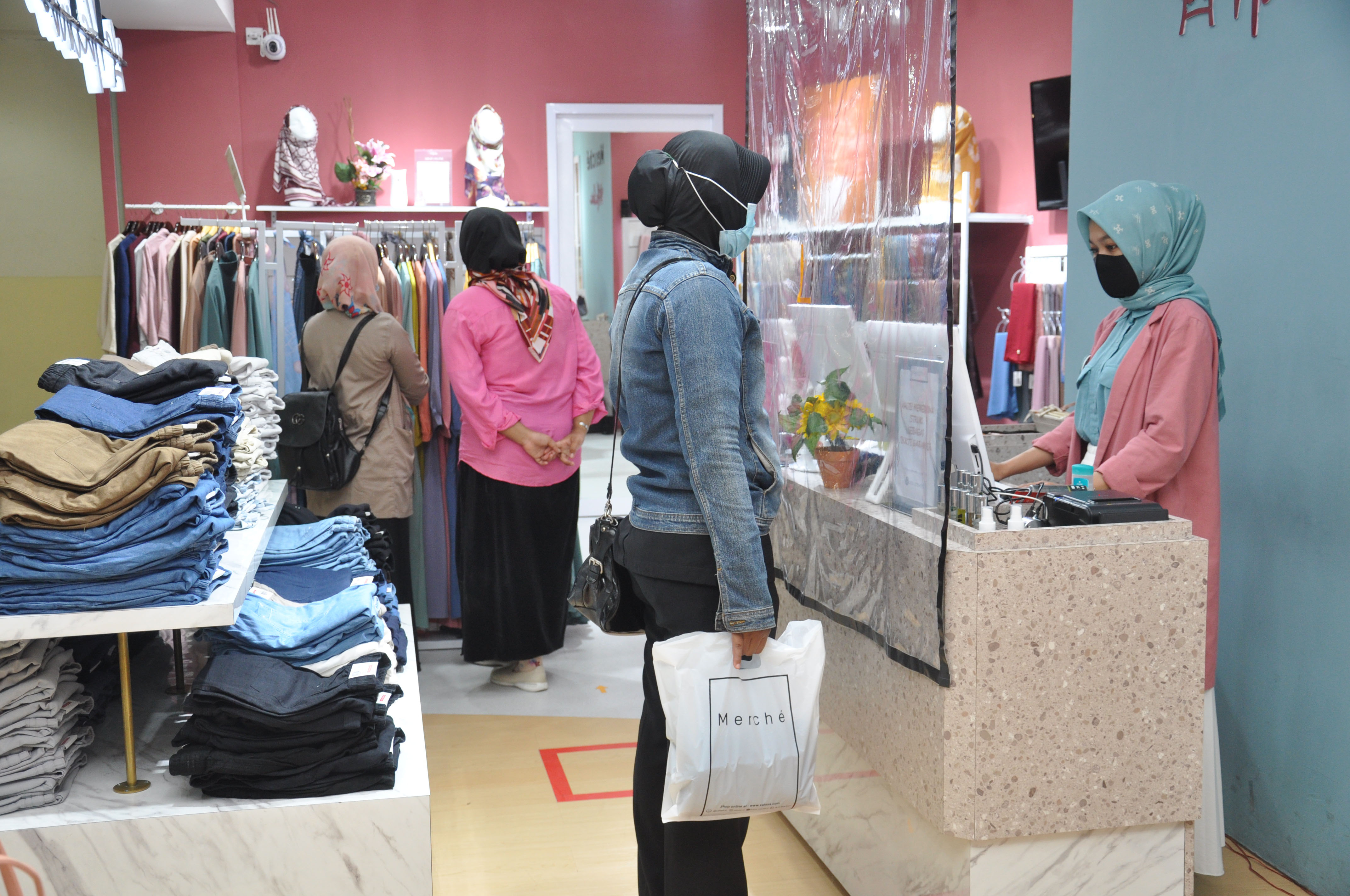 Pembeli melakukan pembayaran dari balik plastik pembatas di Plaza Medan Fair, Sumatera Utara.