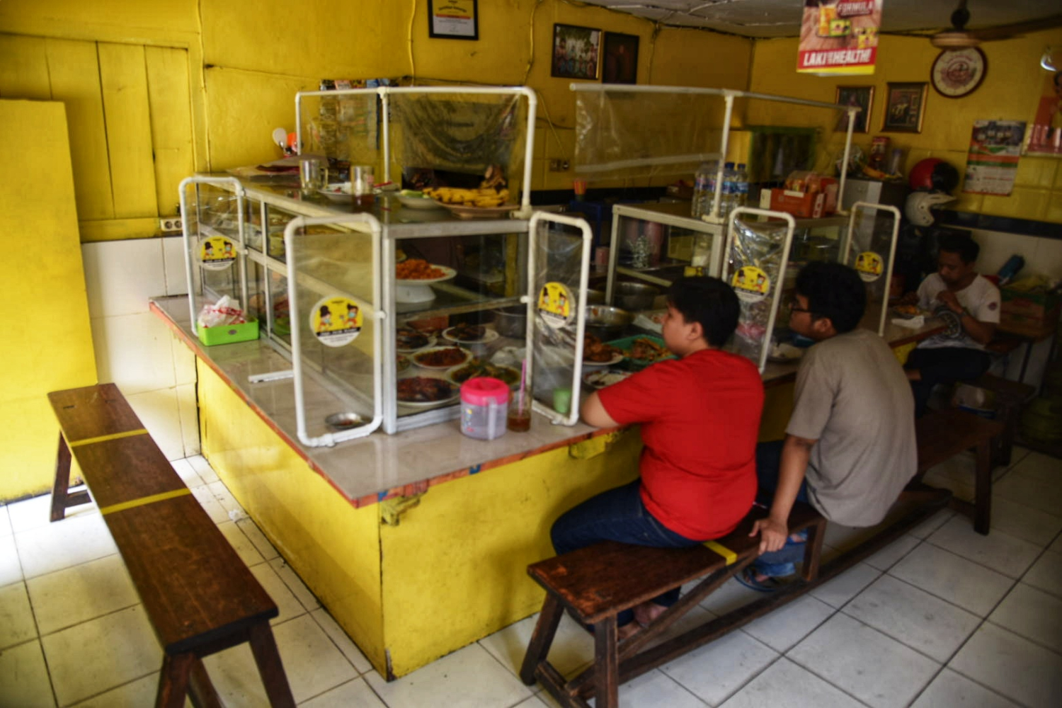 Warga menyantap hidangan makanan di Warteg yang menerapkan protokol kesehatan di kawasan Cilandak Timur, Jakarta Selatan, Minggu (19/7).