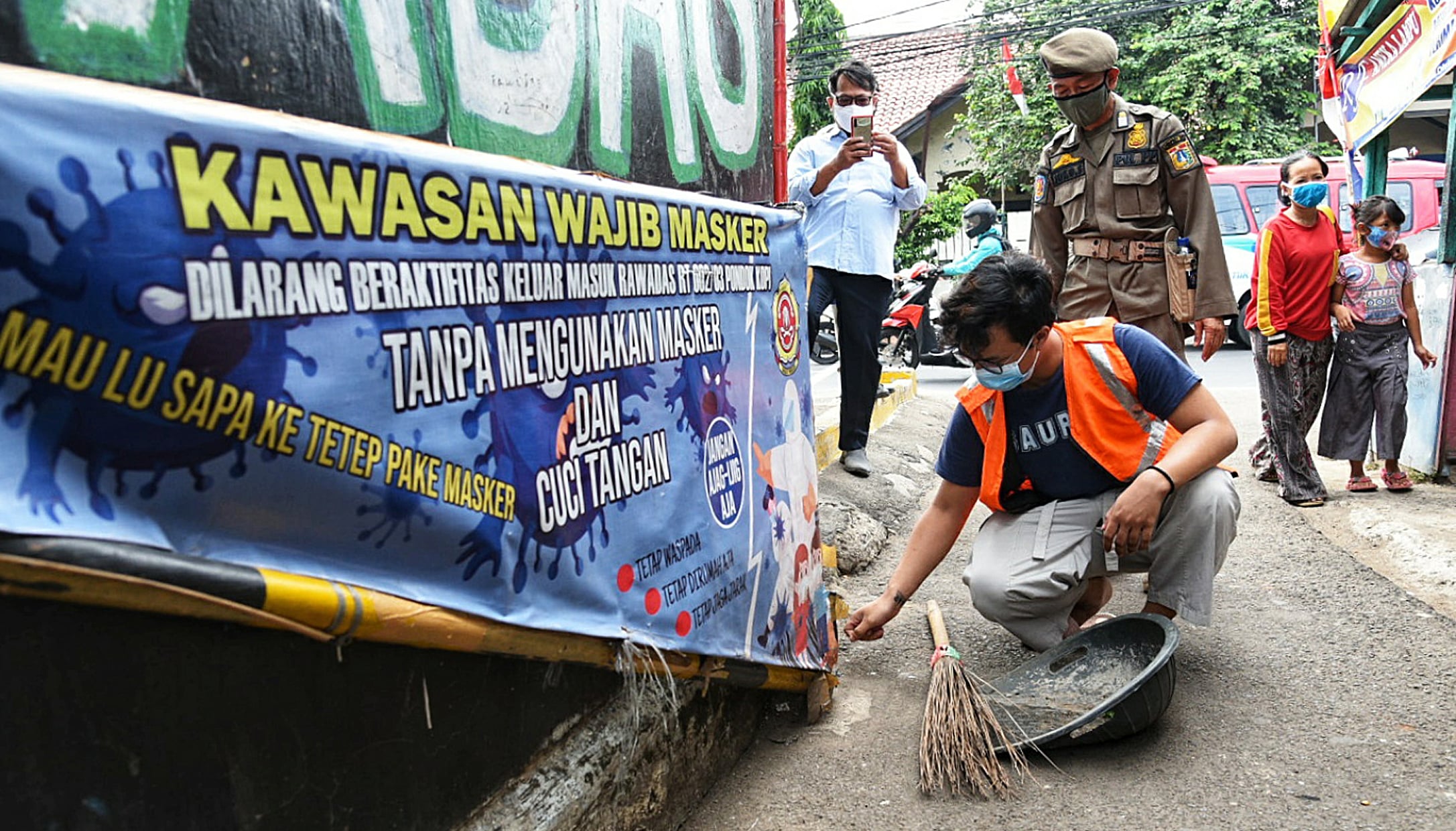 Petugas Satpol PP memberi sanksi sosial terhadap warga yang tidak memakai masker dengan menyapu jalan di kawasan Pondok Kopi, Jakarta Timur