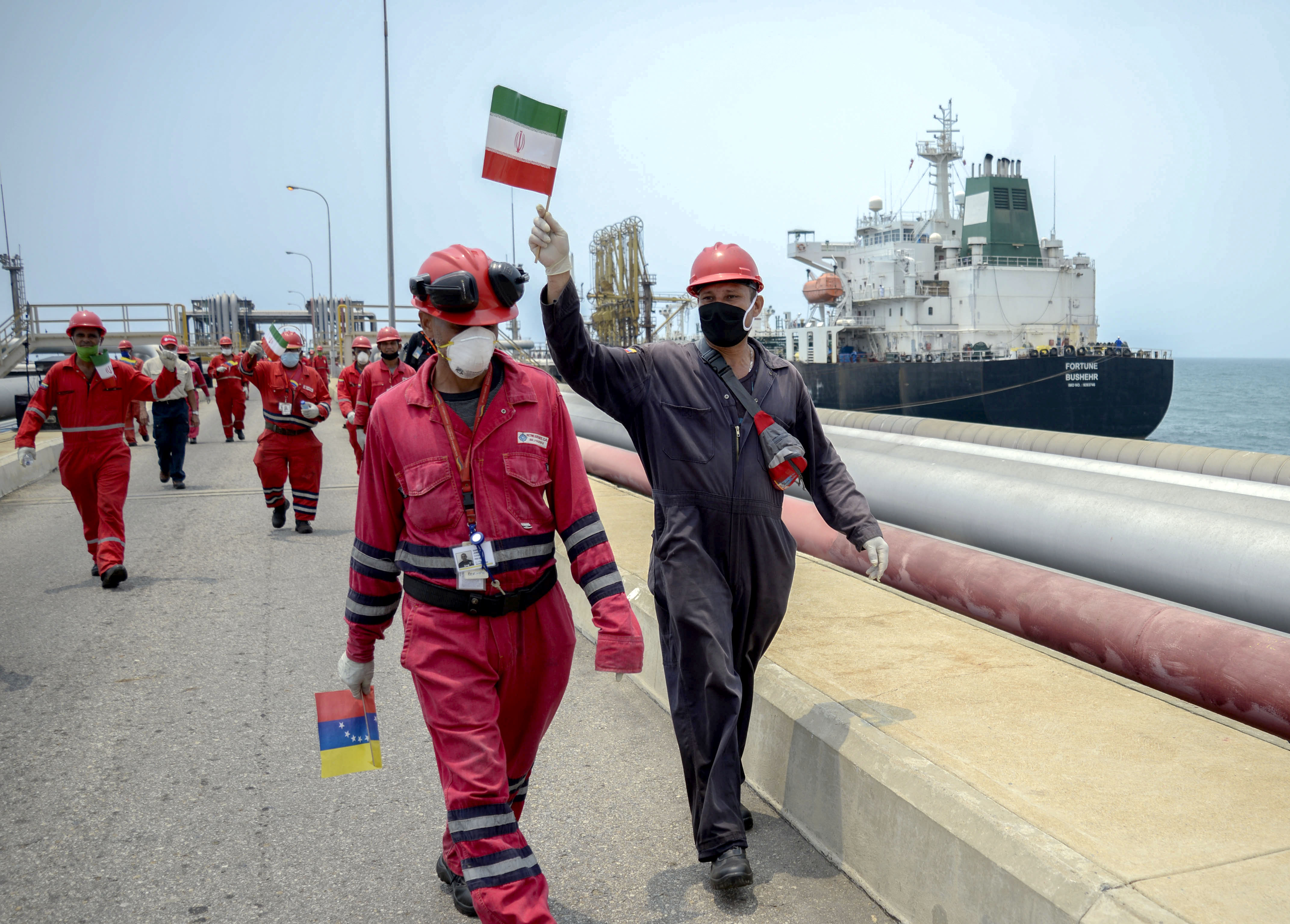 Foto diambil pada 25 Mei 2020, seorang pekerja dari perusahaan minyak negara Venezuela PDVSA mengibarkan bendera Iran.