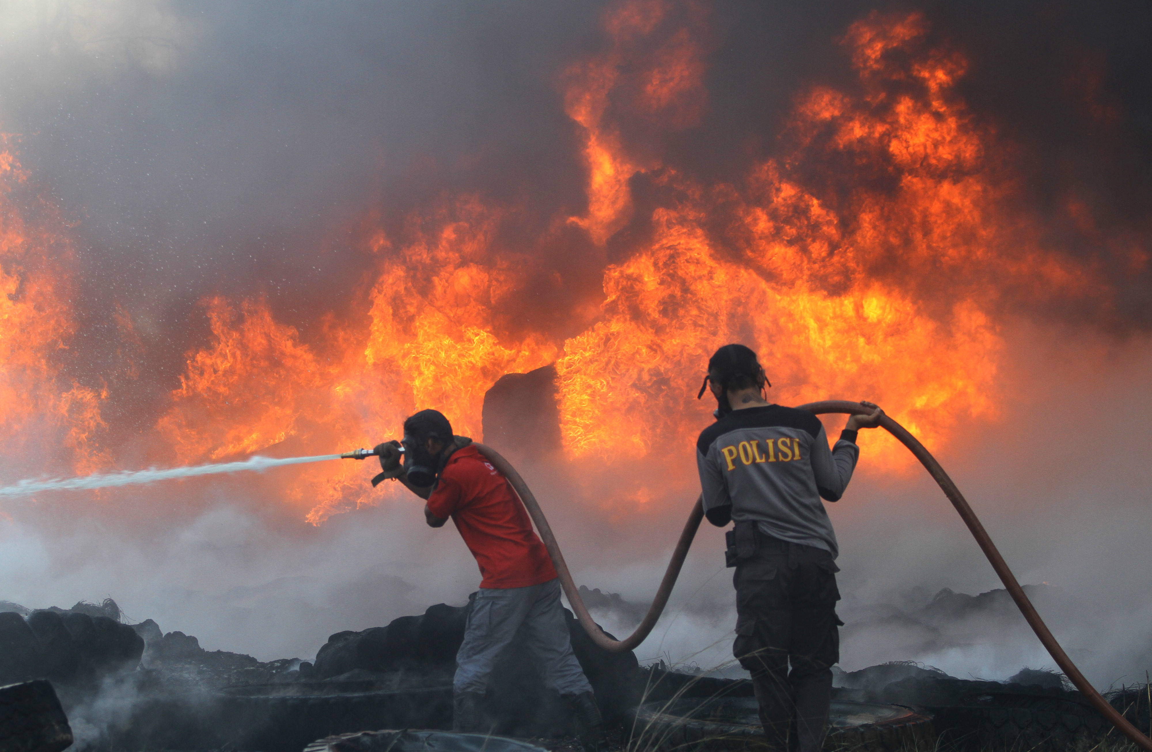 Satgas Karhutla dari TNI, Polri bersama relawan pemadam kebakaran berupaya memadamkan kebakaran lahan yang menjalar ke tumpukkan ban bekas