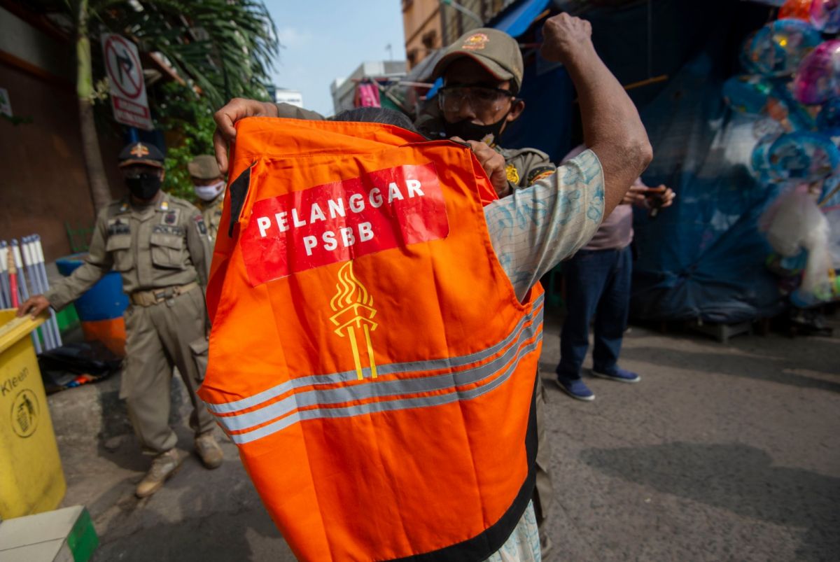 Petugas Satpol PP mengenakan rompi khusus kepada pelanggar PSBB Jakarta