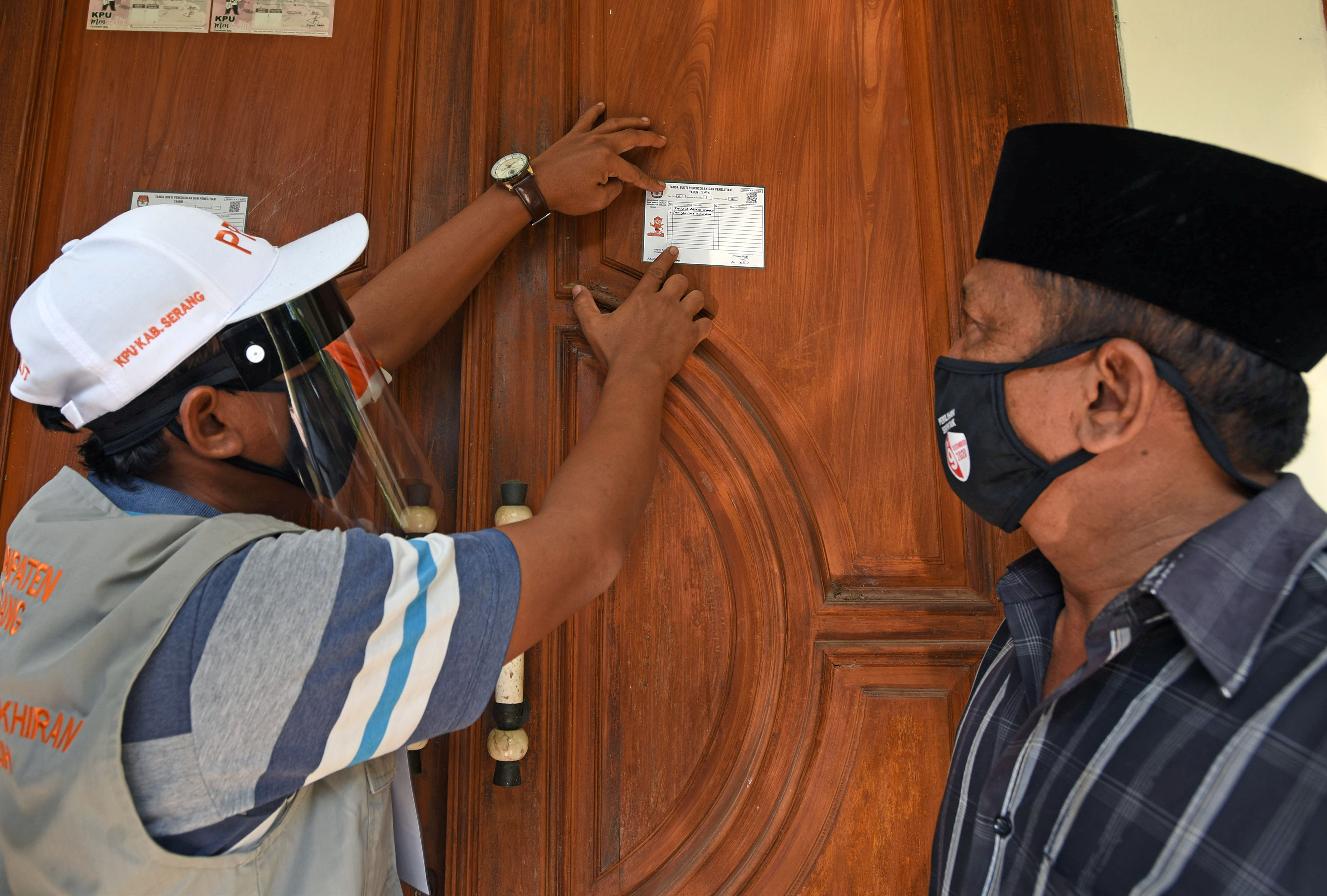 Petugas Pemutakhiran Data Pemilu (PPDP) KPU Kabupaten Serang (kiri) menempel stiker usai melakukan coklit di rumah warga.