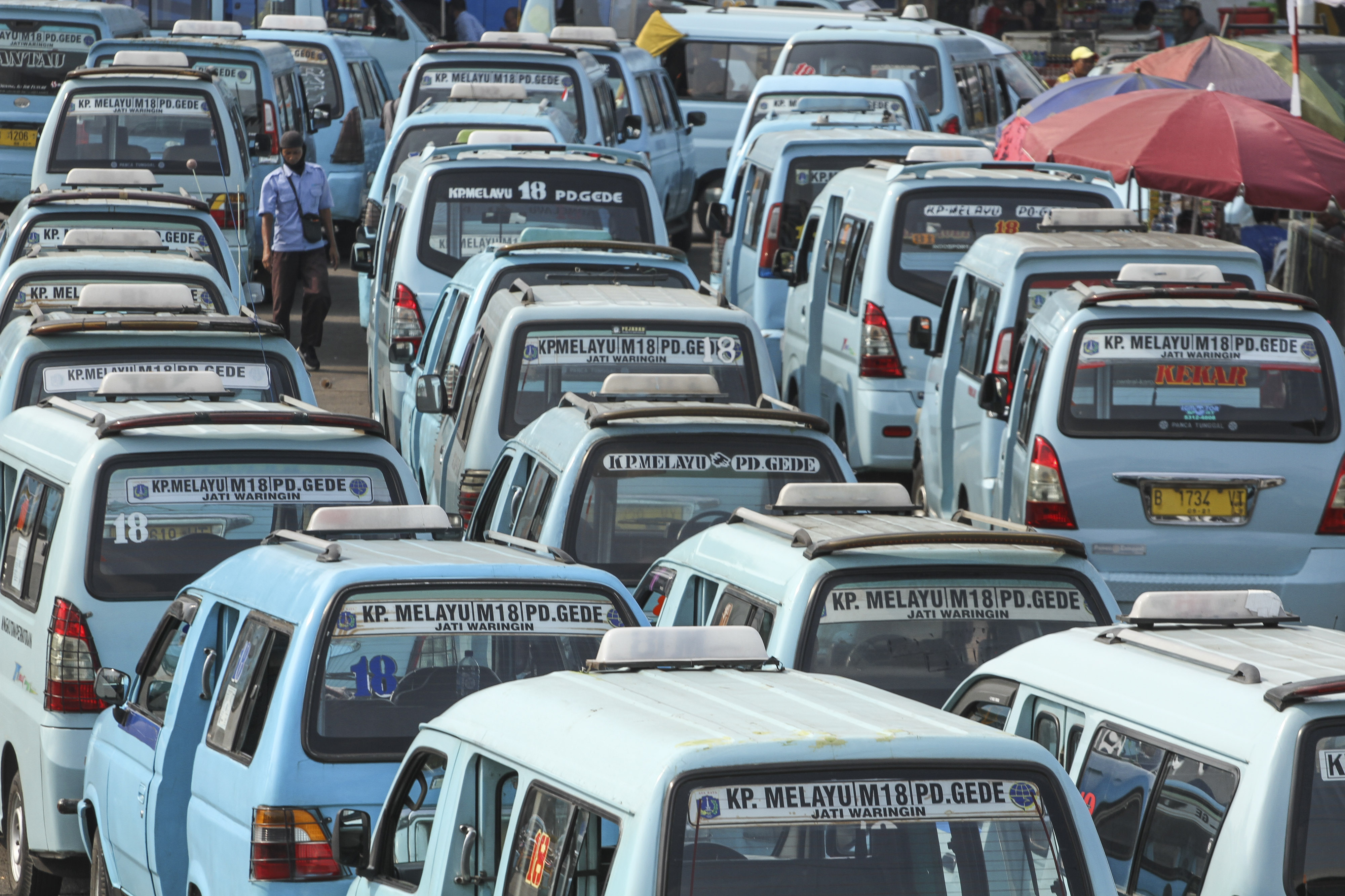 Calon penumpang berjalan di antara deretan angkutan kota di Terminal Kampung Melayu, Jakarta.