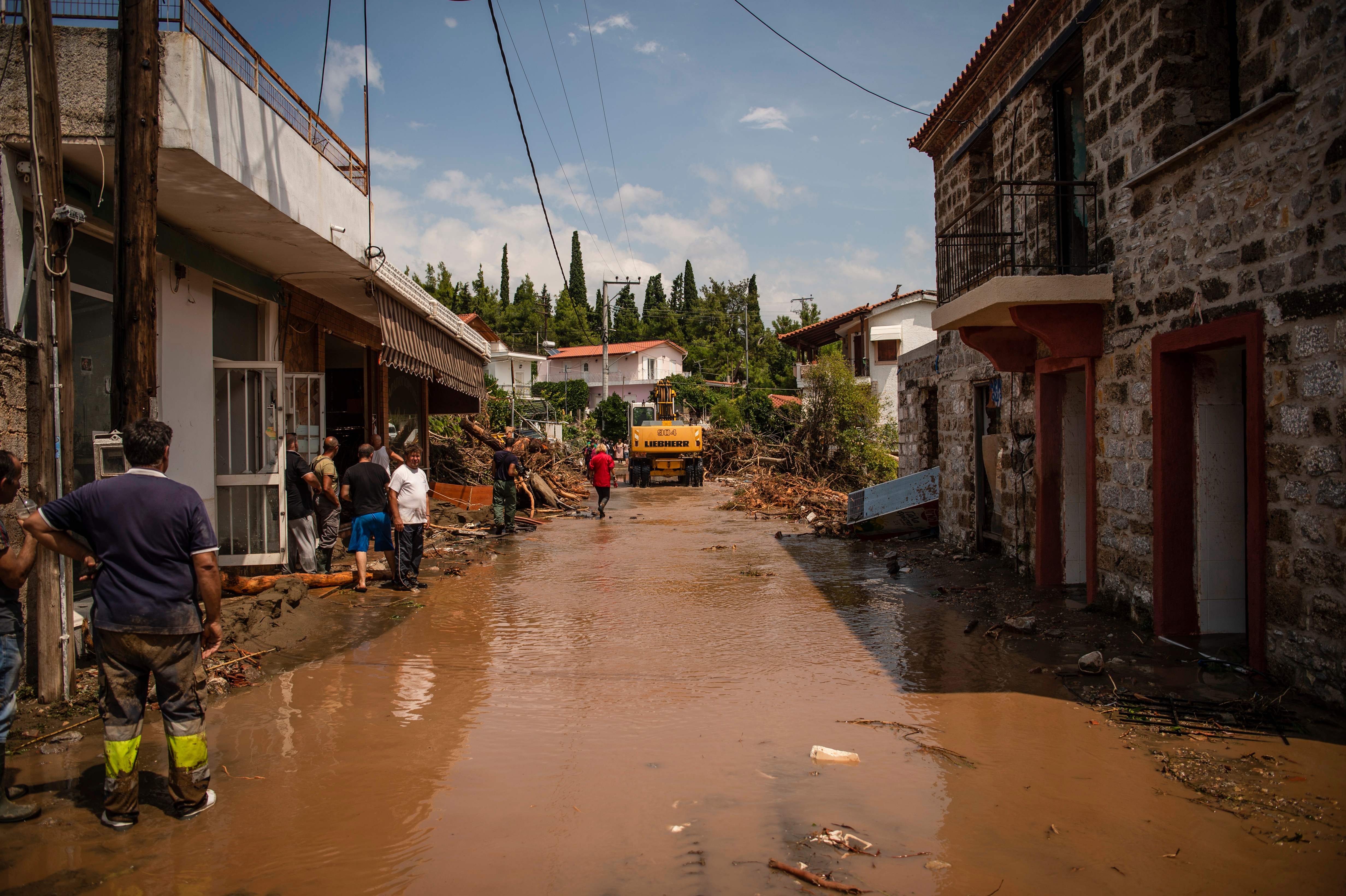 Warga berdiri di jalan yang rusak di Pulau Evia, Yunani.