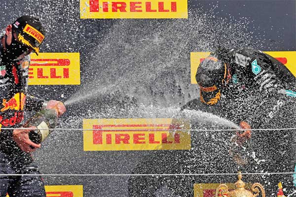 Pembalap Mercedes Lewis Hamilton (kanan) seusai menjuarai GP Inggris merayakan kemenangan di podium