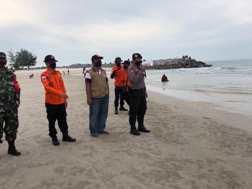 Petugas mengimbau masyarakat yang sedang liburan di pantai untuk memakai masker sekaligus membagi masker