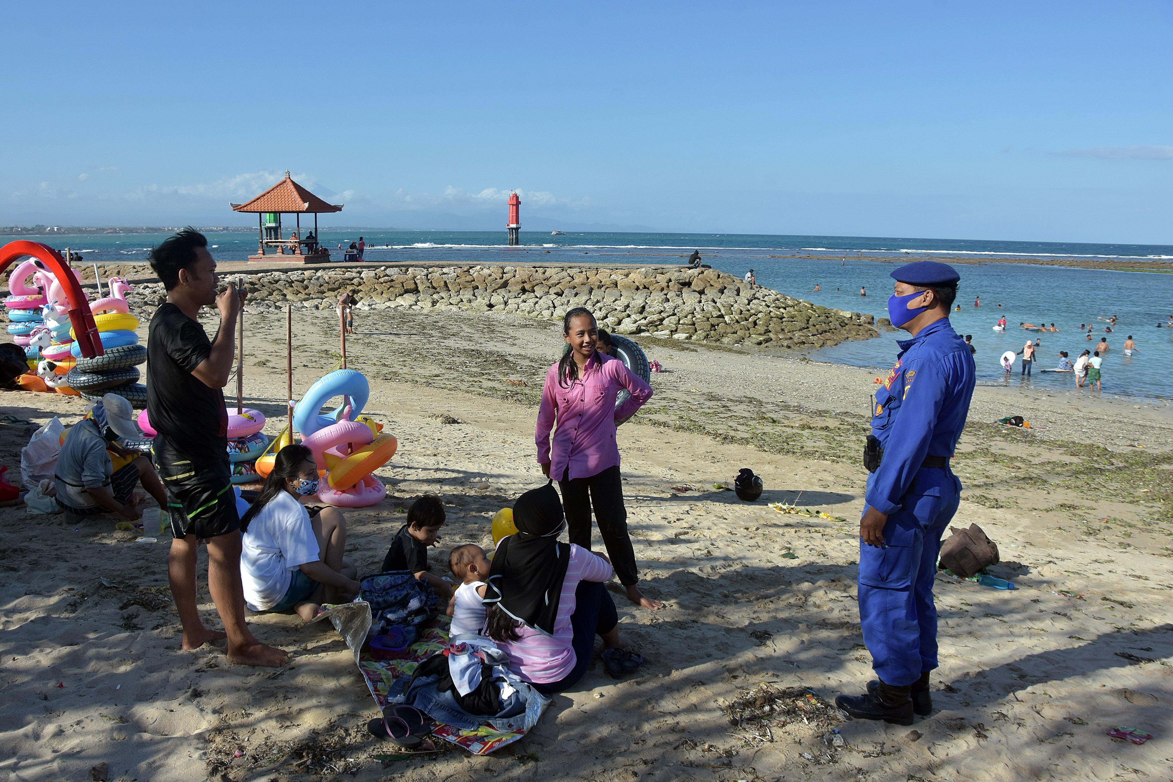 Polisi menegur wisatawan yang tidak menggunakan masker saat liburan Tahun Baru Islam 1442 Hijriah di Pantai Sanur, Denpasar, Bali.