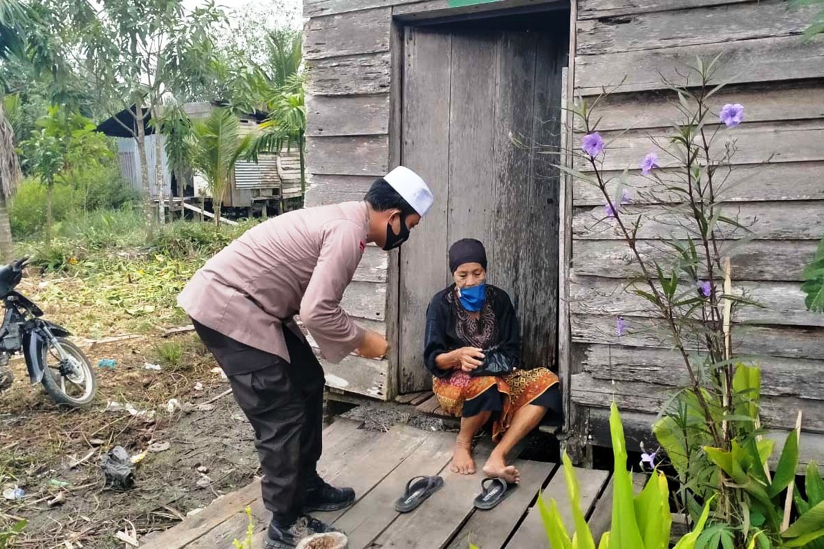 Kapolres Tanjungjabung Barat AKBP Guntur Saputro menyerahkan langsung daging sapi kurban kepada seorang ibu tua di desa terisolasi.